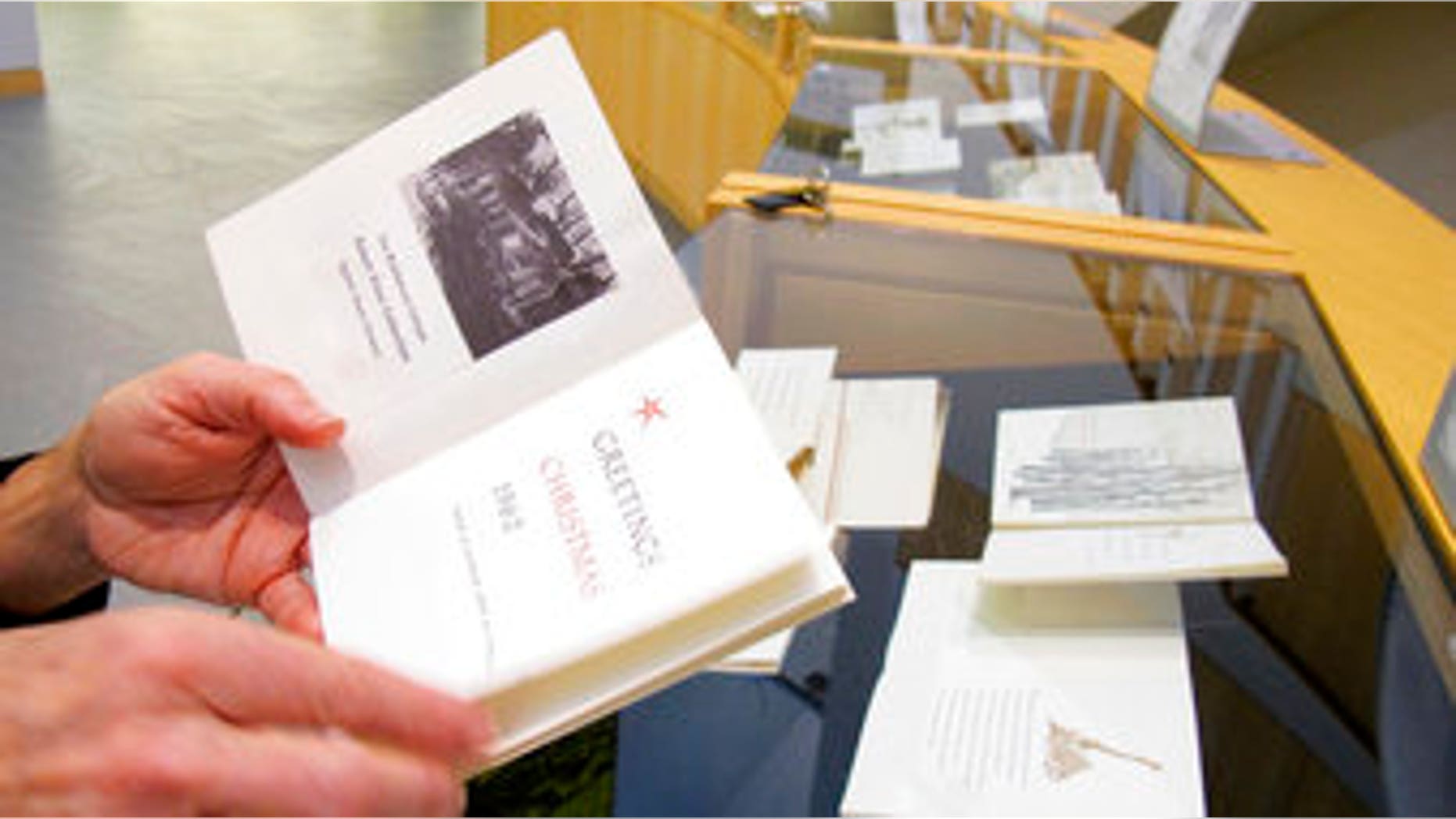 Middlebury College Archivist Danielle Rougeau holds a Christmas card sent by poet Robert Frost in 1962, shortly before his death. The cards include Frost poems and artwork done by different artists.