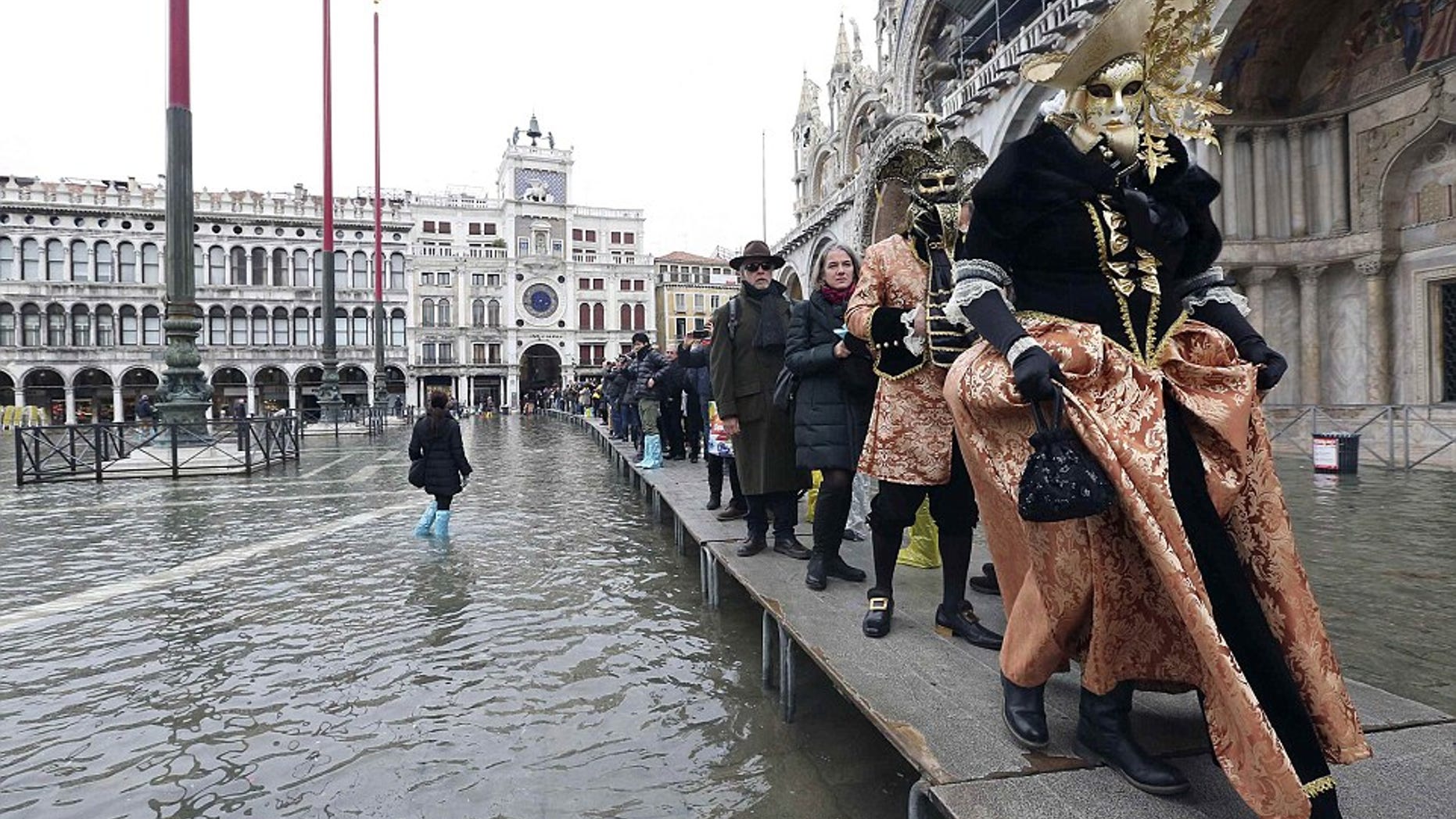 Tourists navigate Venice's city center on narrow wooden platforms.