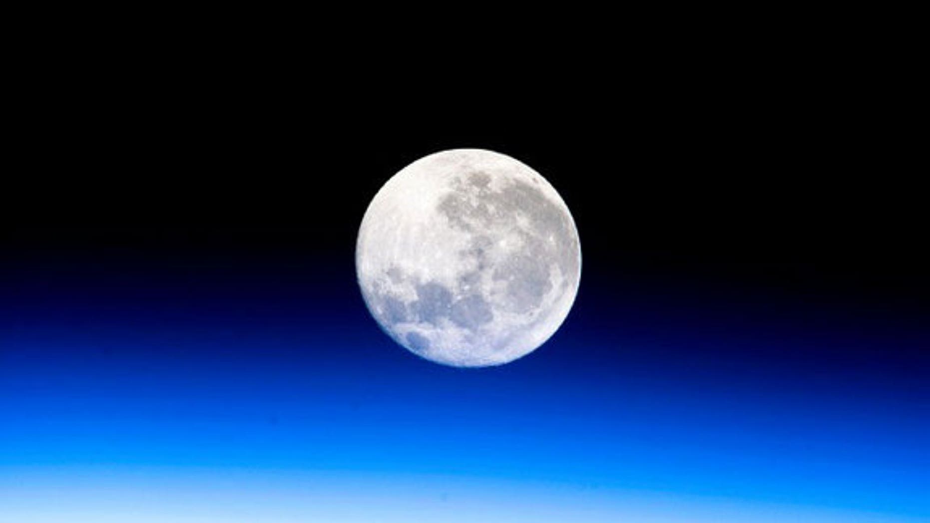 A full moon is visible in this view above Earth's horizon and airglow, photographed by Expedition 10 Commander Leroy Chiao on the International Space Station.