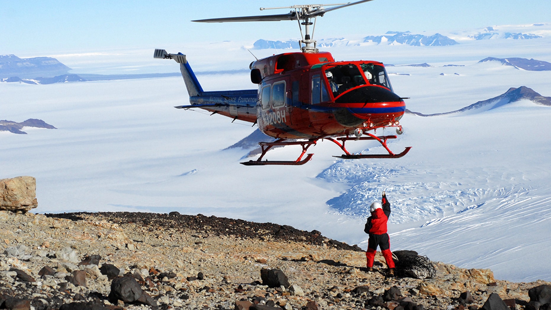 A helicopter prepares to transport fossil cargo over the ice and back to the Field Museum paleontologists' field camp, at the Beardmore Glacier in Antarctica.