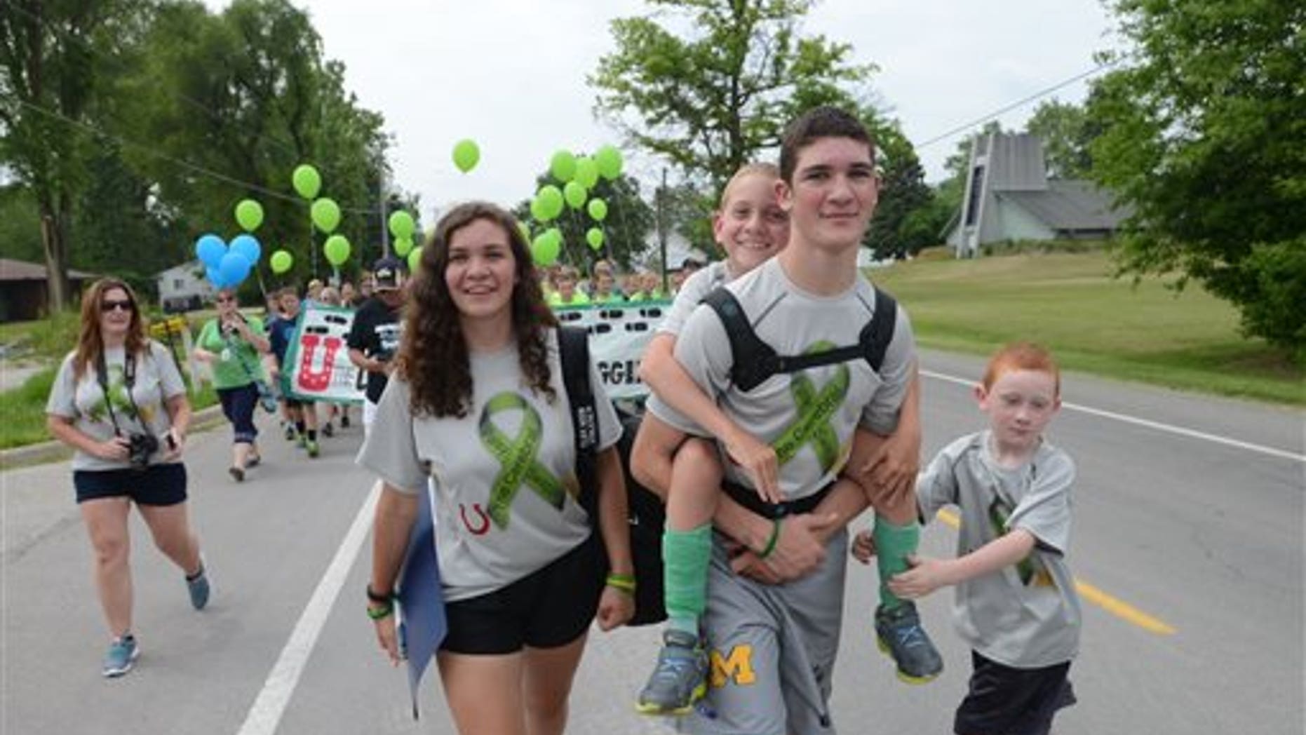 Braden Gandee rides aboard his brother Hunter's back who is walking along side sister, Kerragan and brother, Kellen as the Gandee family begins the 55 mile walk from Temperance, Mich., to Ann Arbor Friday, June 5, 2015. This walk is to raise awareness about cerebral palsy. (Tom Hawley/The Monroe Evening News via AP)