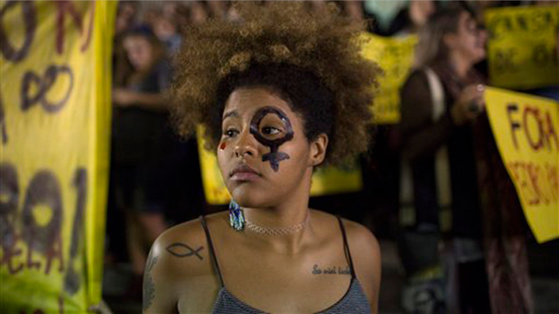 A woman wearing a female gender symbol attends a protest against the gang rape of a 16-year-old girl in Rio de Janeiro, Brazil, Friday, May 27, 2016. The assault last Saturday came to light after several men joked about the attack online, posting graphic photos and videos of the unconscious, naked teen on Twitter. (AP Photo/Leo Correa)