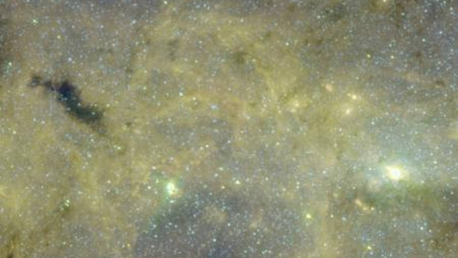 In this image, taken by NASA's Spitzer Space Telescope, the mysterious gas cloud G0.253+0.016 is the black object on the left. The Milky Way's center is the bright spot at right.