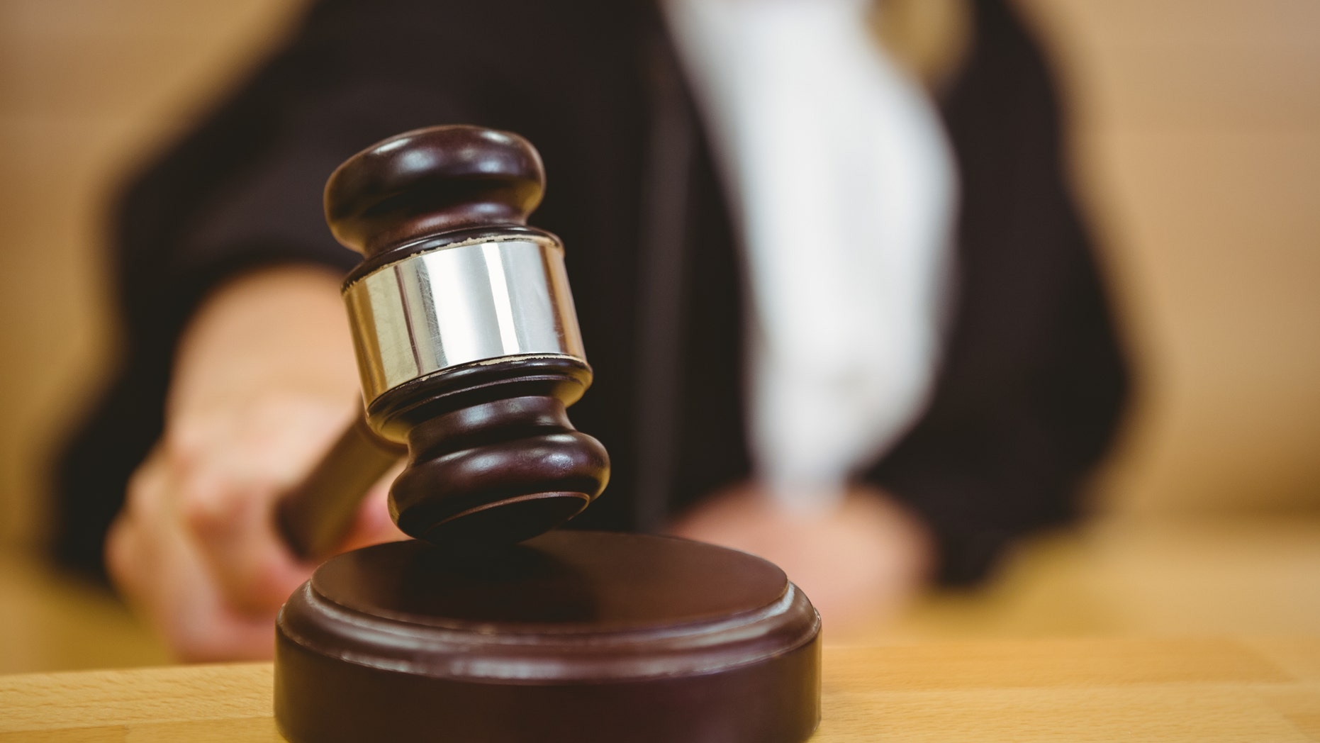 Hand about to bang gavel on sounding block in the court room