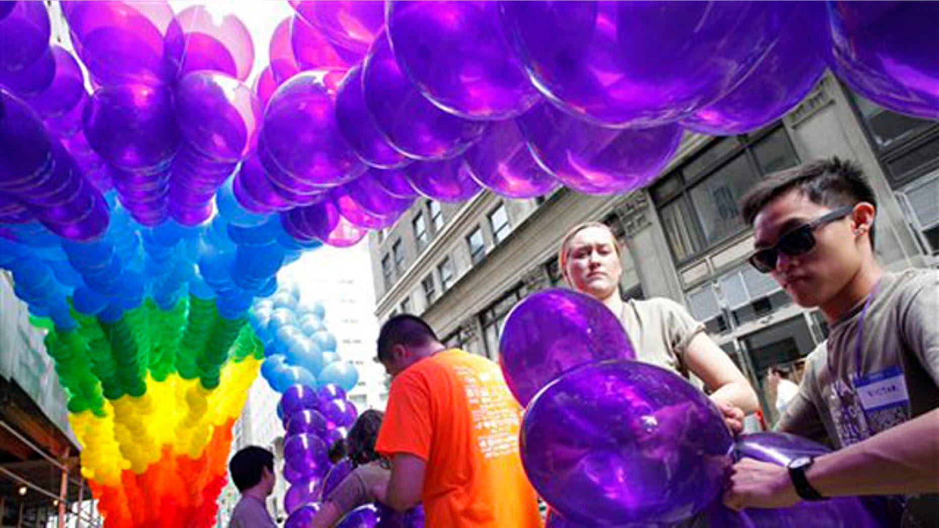Kajsa Westman, second from right, of Stockholm, Sweden, and Victor Ng, right, of Seattle, tie balloons to a banner in preparation for the annual Gay Pride parade, Sunday, June 26, 2011 in New York. One of the world's oldest and largest gay pride parades was expected to become a victory celebration Sunday after New York's historic decision to legalize same-sex marriage. The law signed by Gov. Andrew Cuomo on Friday doesn't take effect for 30 days. (AP Photo/Mark Lennihan)