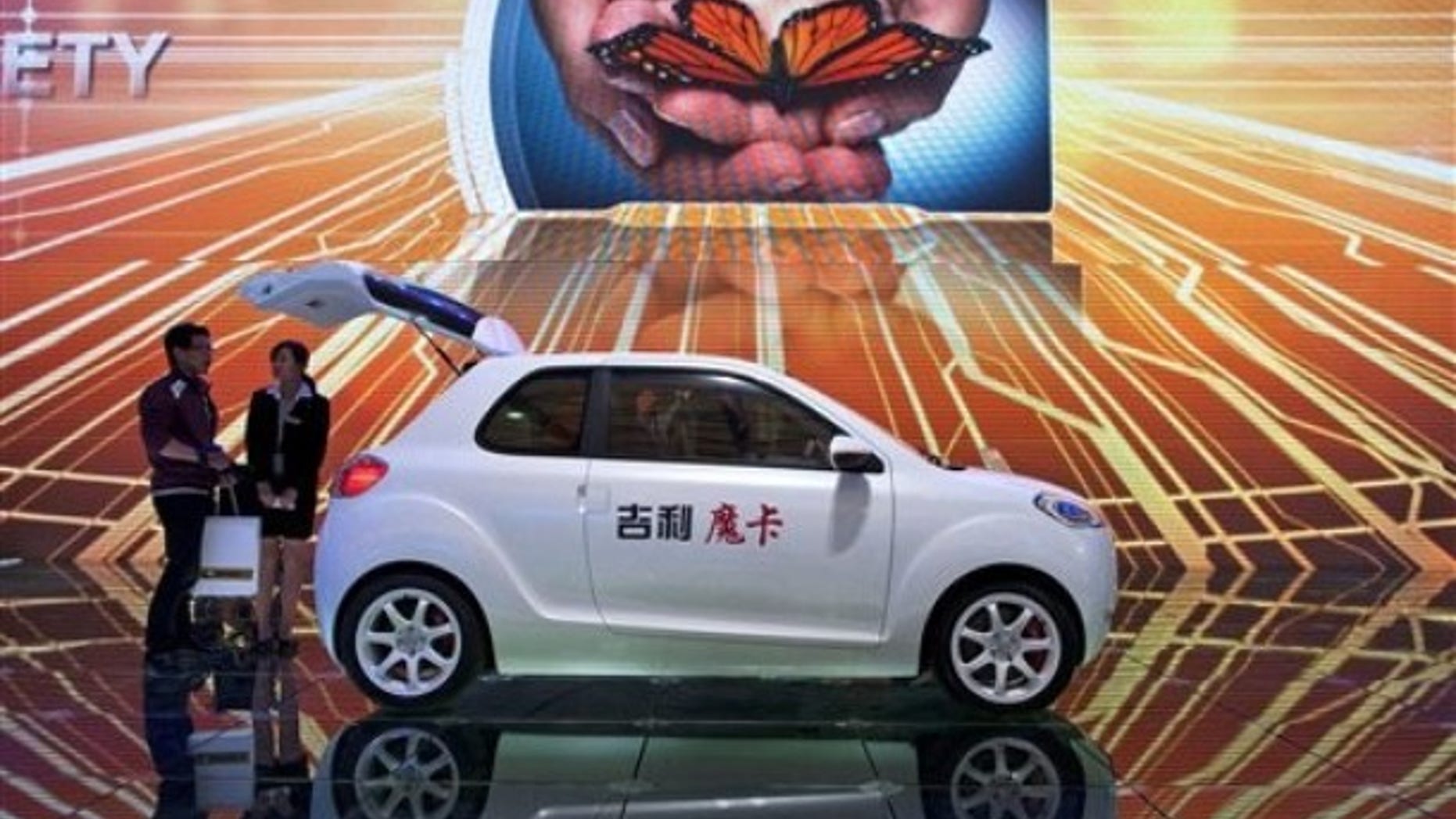 A woman chats with a visitor next to a Geely McCar displayed at the 14th Shanghai International Automobile Industry Exhibition in Shanghai, China Wednesday, April 20, 2011.