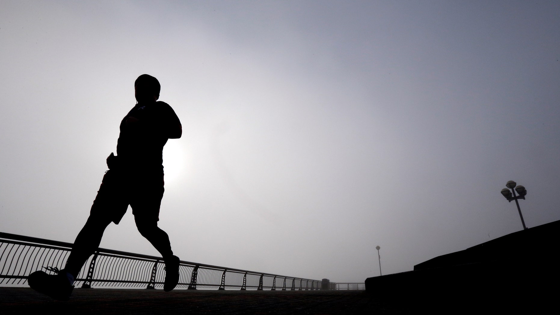 FILE - In this Wednesday, Jan. 15, 2014 file photo, a man jogs at Pier A Park in Hoboken, N.J. Clean living can greatly lower your risk for heart disease even if your genes are heavily stacked against you. A large international study released on Sunday, Nov. 13, 2016 found that people with the highest levels of inherited risk cut their chances of suffering a heart attack or other heart problems in half if they didn't smoke, ate well, exercised and stayed slim. (AP Photo/Julio Cortez, File)