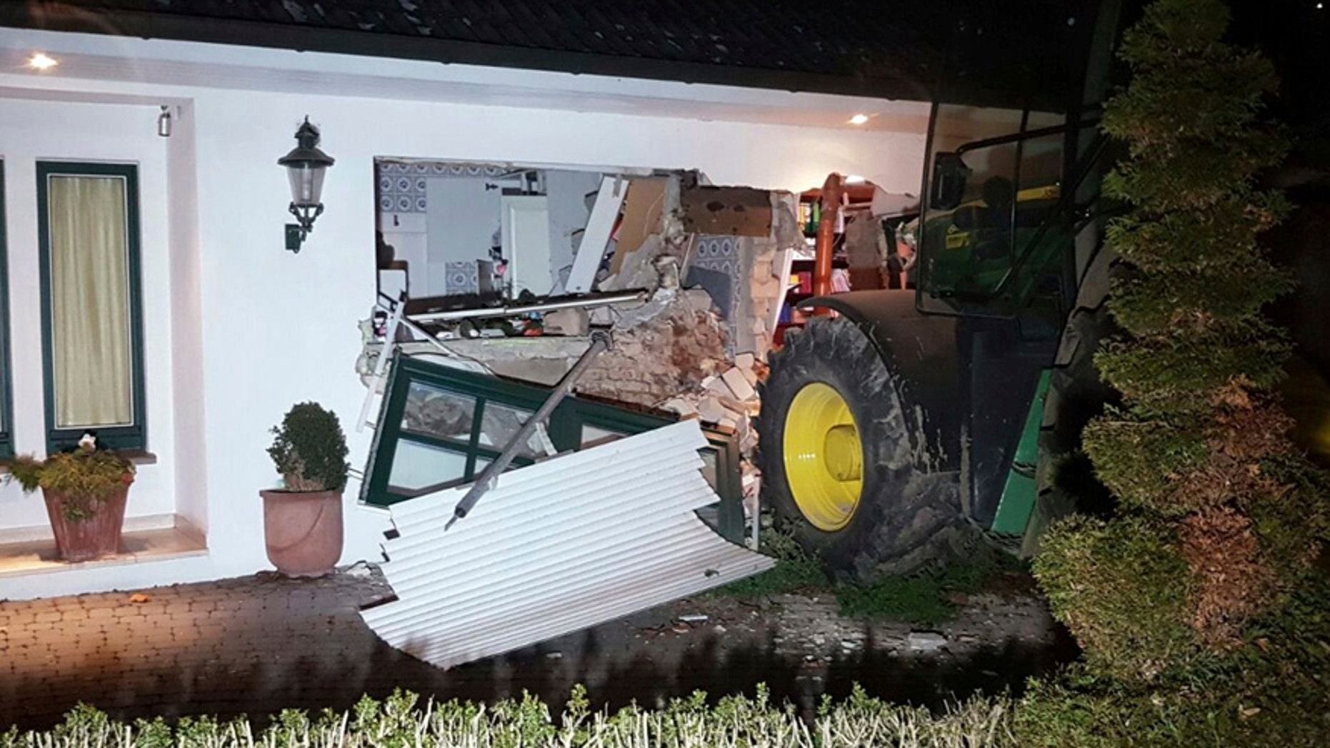 A tractor stands in front of a damaged house after it broke through the wall in Buende, north-western Germany, Thursday, Jan. 26, 2017. Unknown intruders steered the tractor into the house and broke through the wall in order to steal a safe. The residents were not injured. (Nord-West-Media TV/dpa via AP)