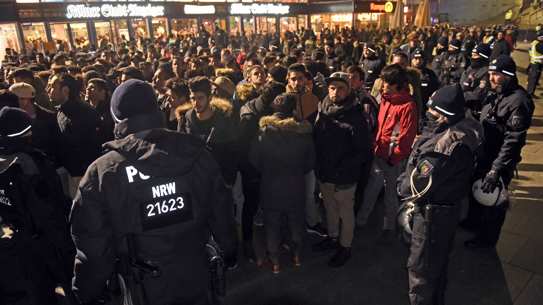 Police officers surround a group of men in front of the Cologne, western Germany, main station, Saturday, Dec. 31, 2016, where a string of robberies and sexual assaults last year that were blamed largely on migrants from North Africa prompted nationwide outrage. (Henning Kaiser/dpa via AP)