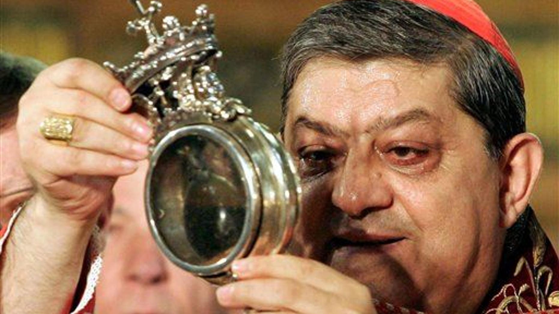 File photo - The archbishop of Naples holds a flask believed to contain drops of liquefied blood of San Gennaro in 2006. (AP Photo/Salvatore Laporta, File)