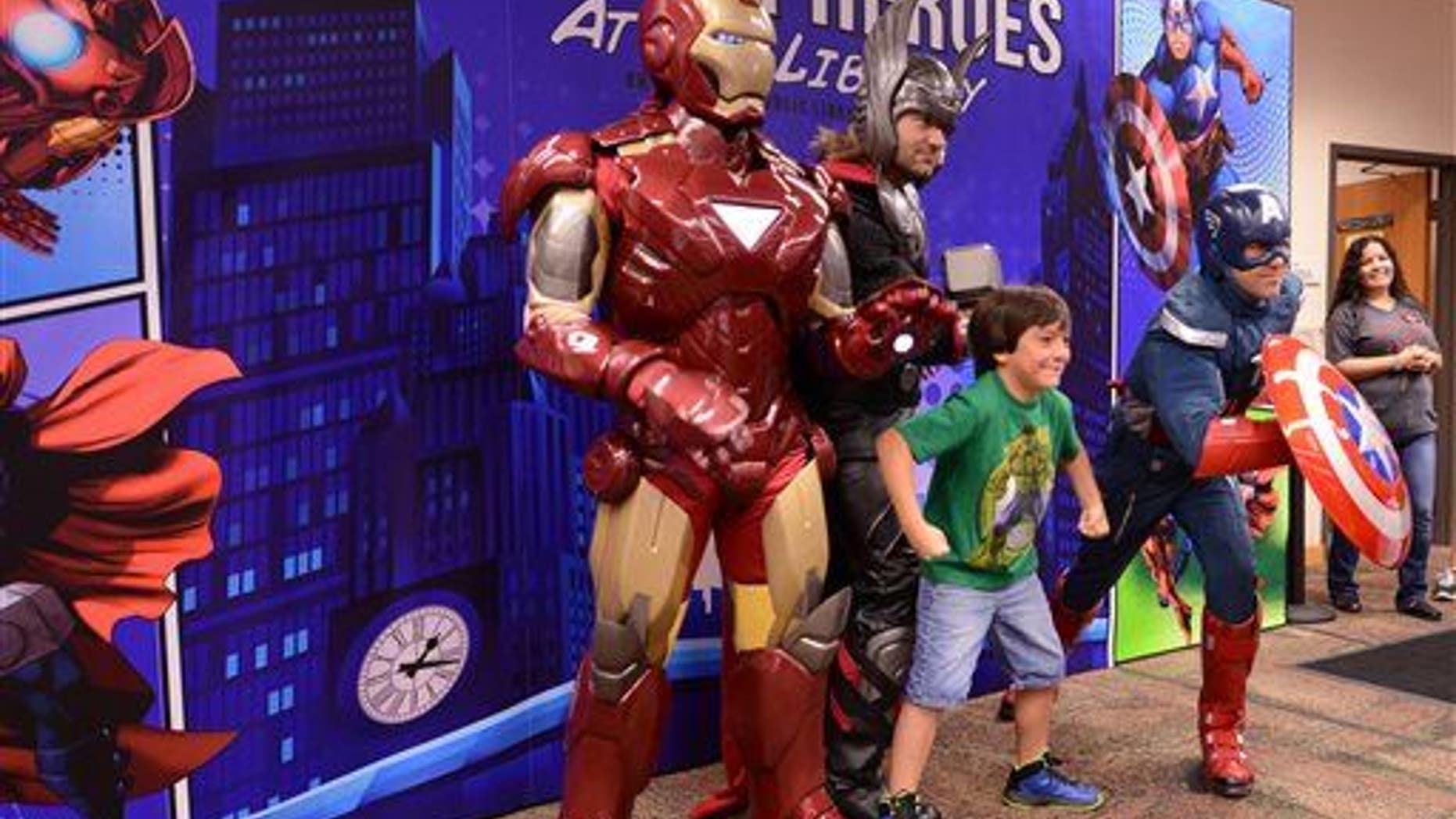 A boy strikes a pose with three superheroes in this file photo.