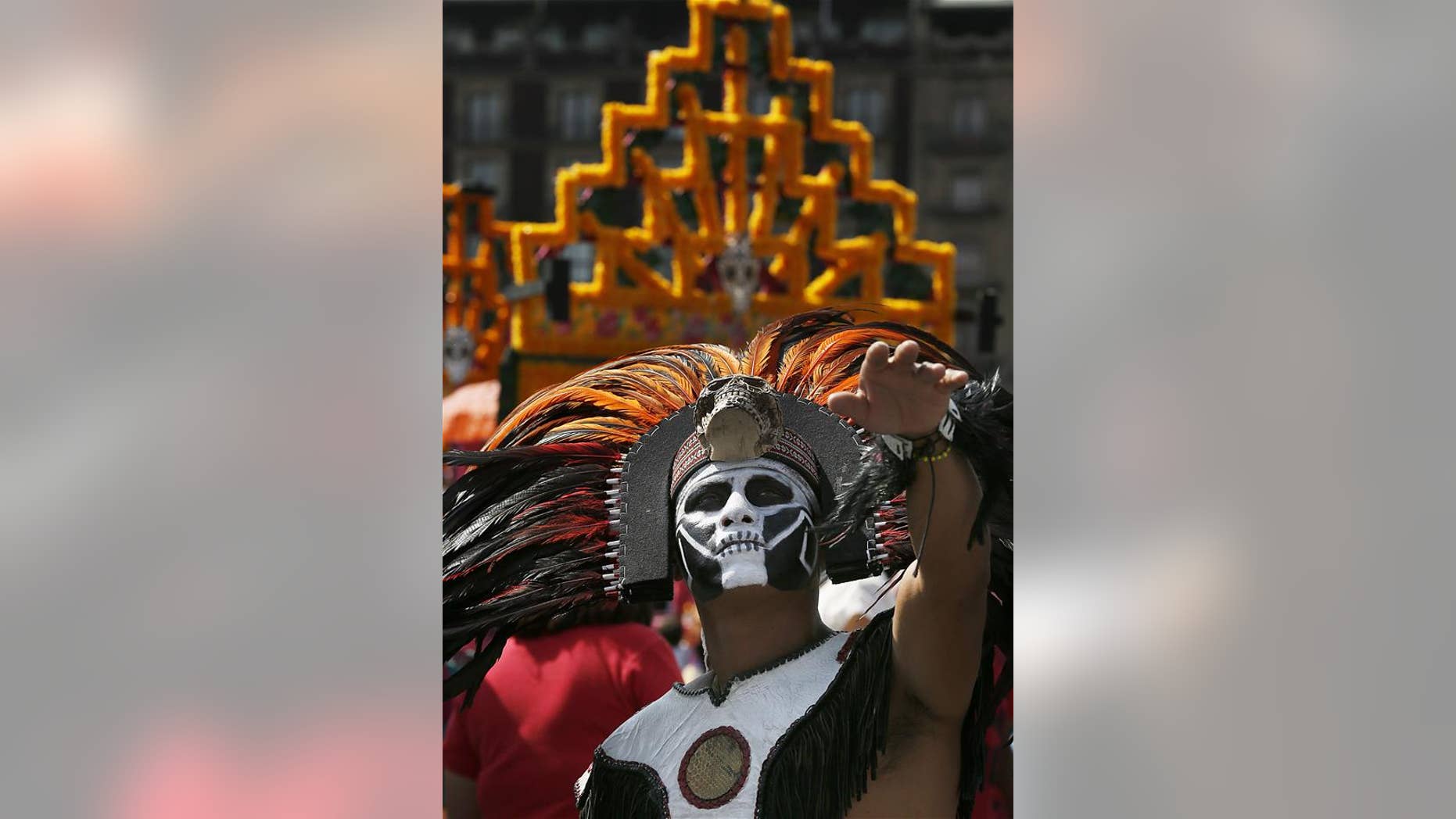 A man with his face painted and dressed as an Aztec Indian gestures during the celebration of the Day of the Dead, in Mexico City, Wednesday, Nov. 2, 2016.