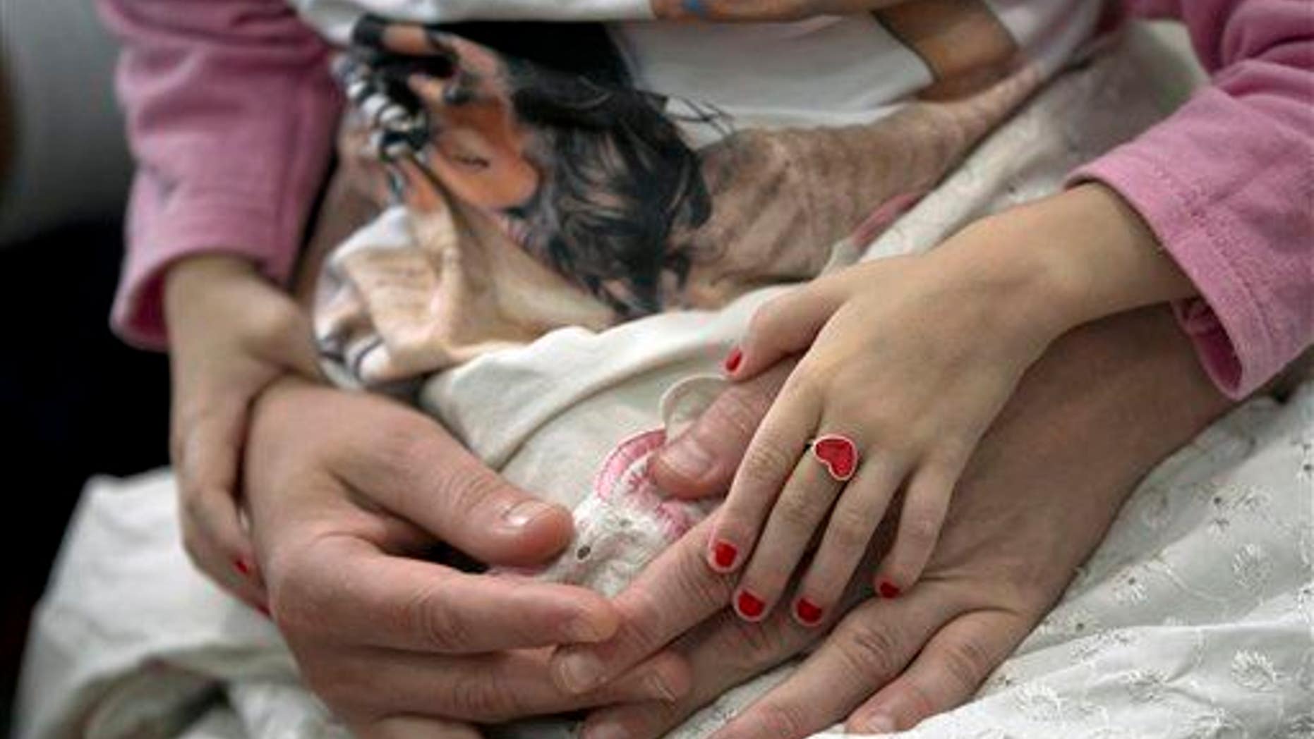 A young girl holds her mother's hands in this file photo.