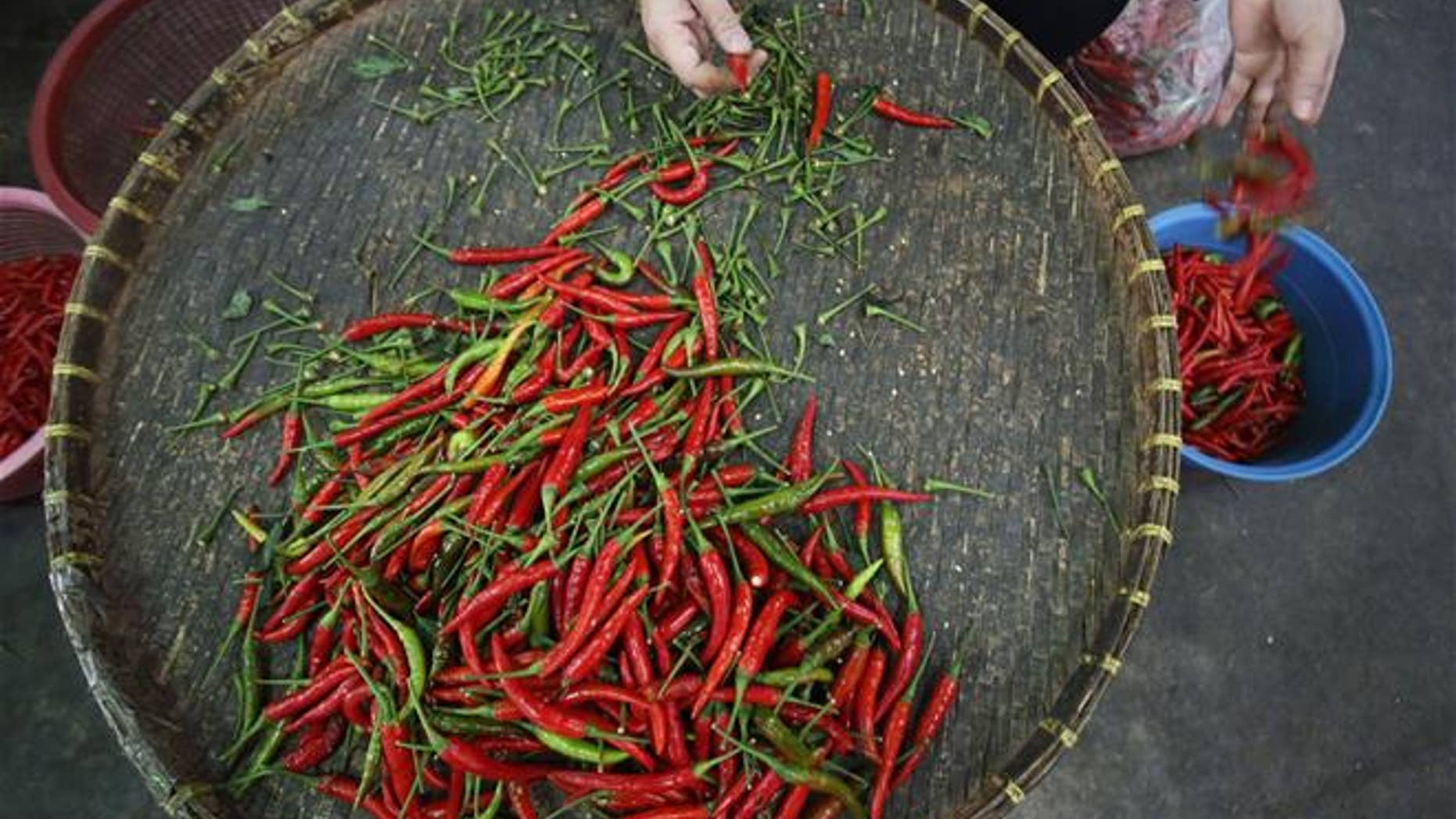 A local vendor sorts through Thai chili peppers in Bangkok.