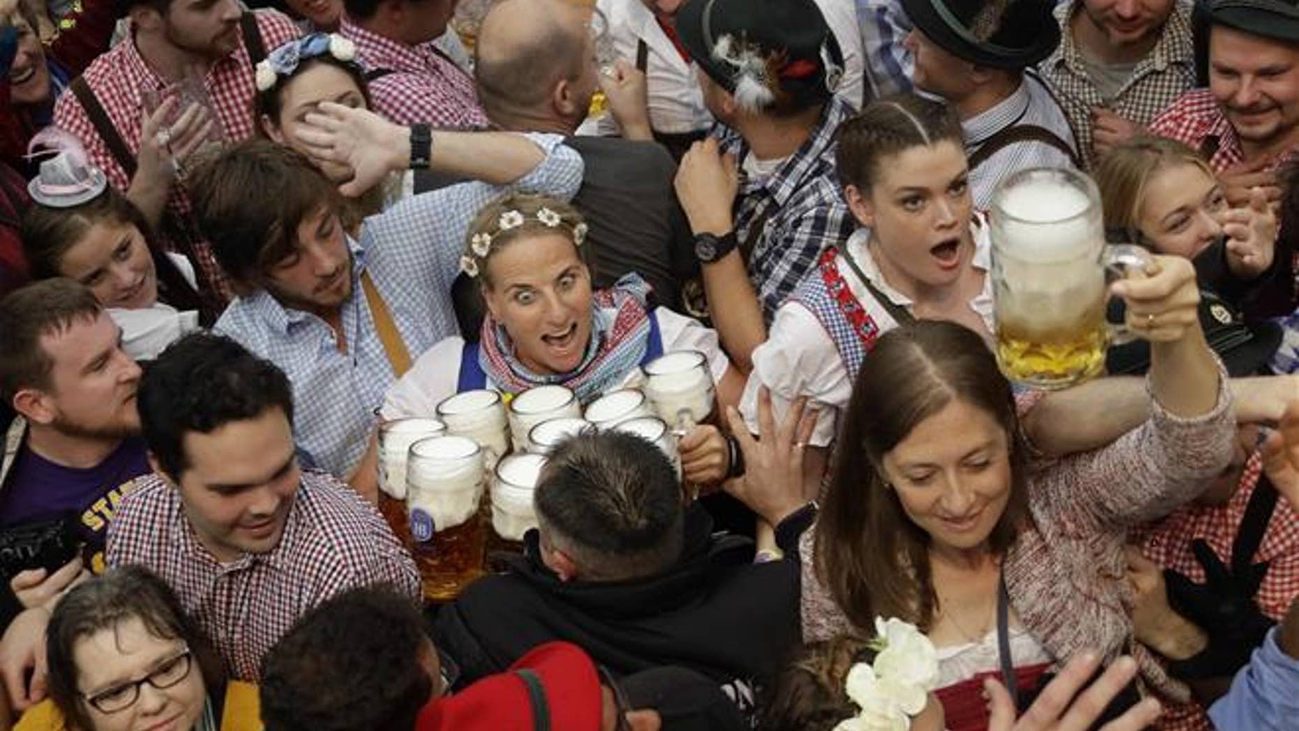 FILE - In this Saturday, Sept. 17, 2016 file photo a waitress is surrounded by visitors during the opening ceremony of the 183rd Oktoberfest beer festival in Munich, southern Germany.