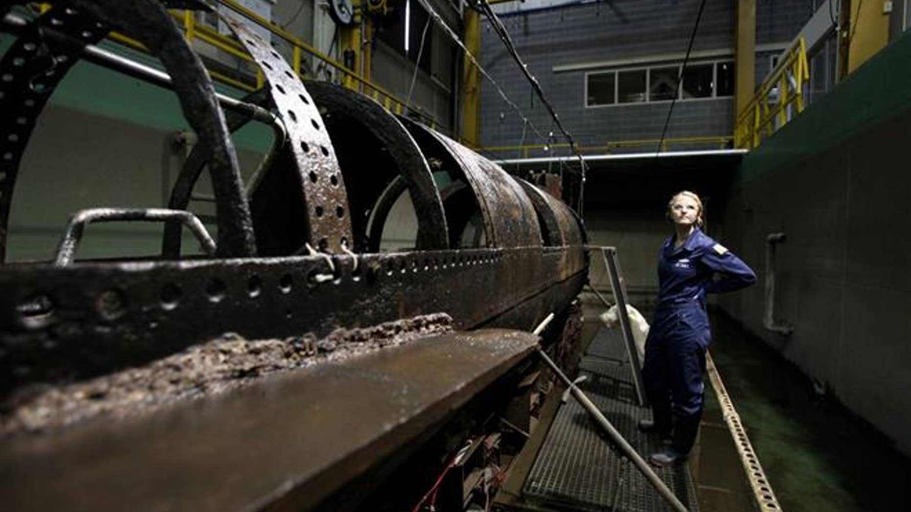 Conservator Anna Funke stands next to the HL Hunley at the Warren Lasch Conservation Center on Wednesday. (Michael Pronzato/The Post And Courier via AP)