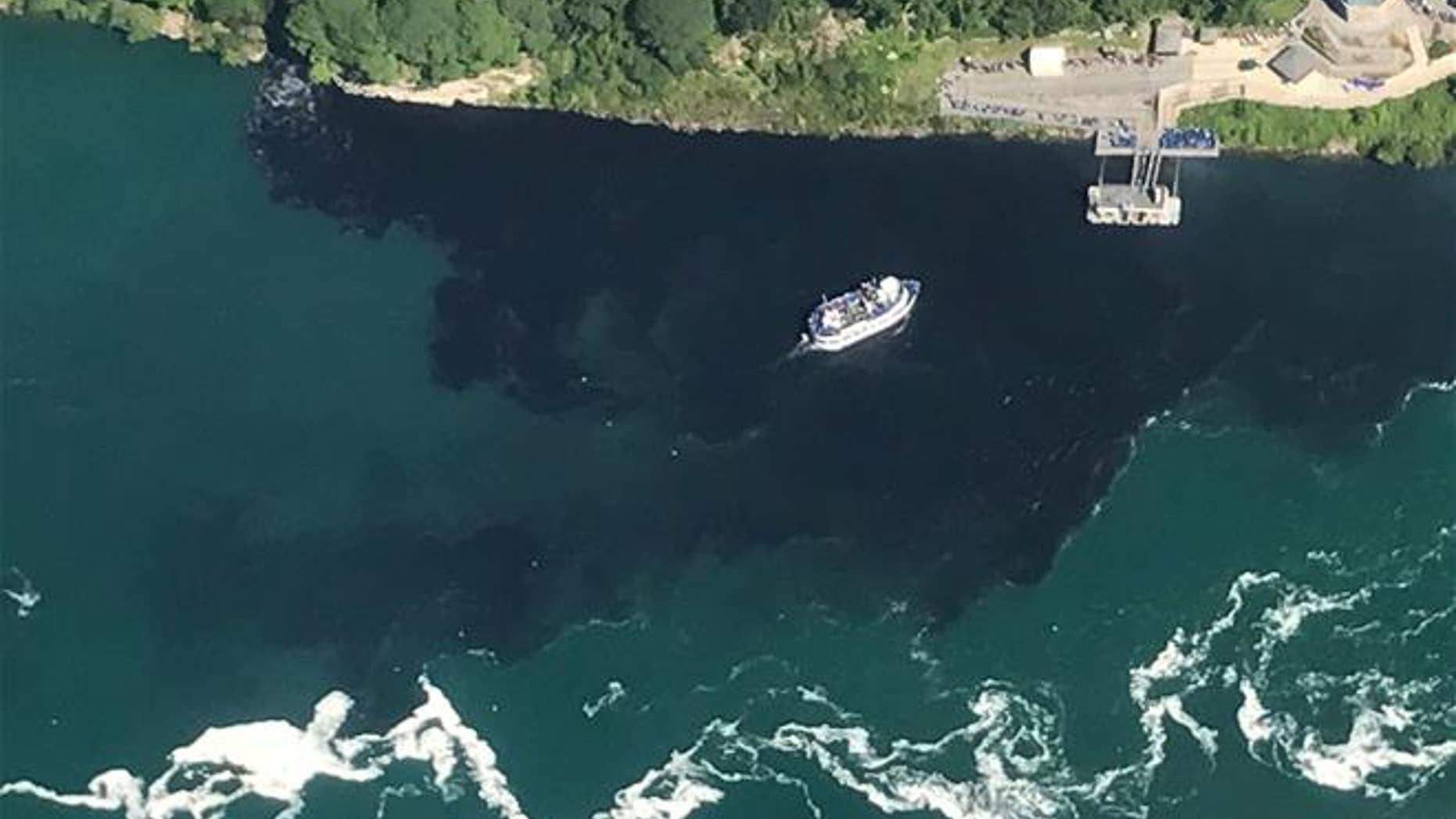 Black-colored wastewater treatment discharge is released into water below Niagara Falls.