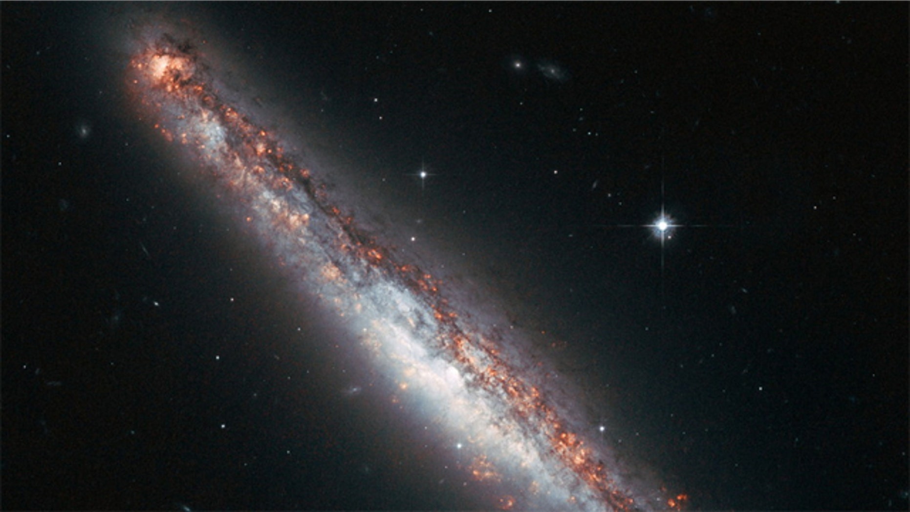 This NASA/ESA Hubble Space Telescope image shows the edge-on profile of the slender spiral galaxy NGC 5775, which is surrounded by a halo of gas that astronomers suspect is kicked up by star explosions like a galaxy-size fountain.
