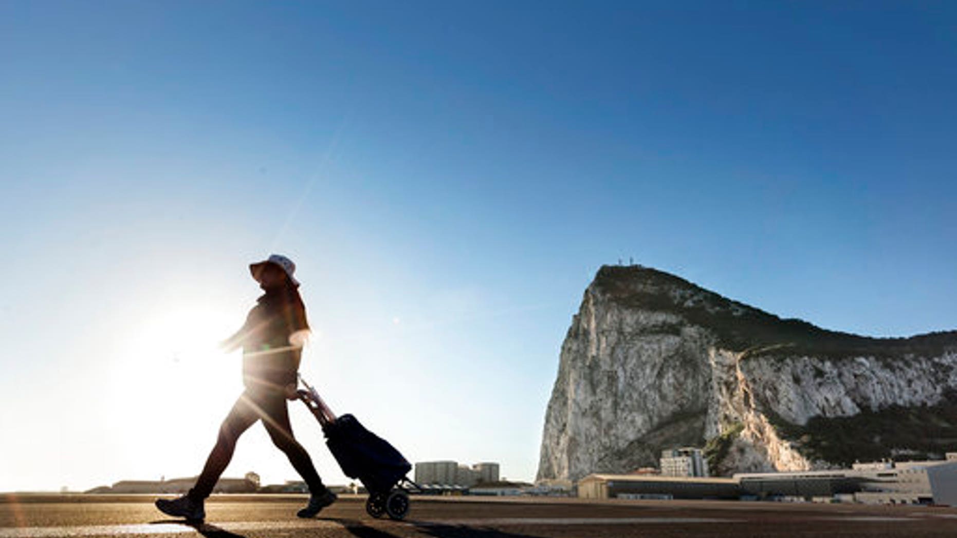 A woman walks on the Spanish side of the border between Spain and the British overseas territory of Gibraltar with the Rock as a background, in La Linea de la Concepcion, Southern Spain.