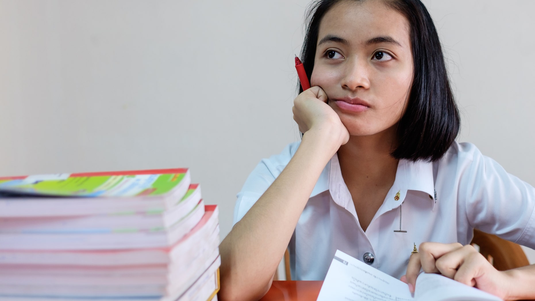 selective focus on thai young adult woman student in uniform reading a book in library with stress
