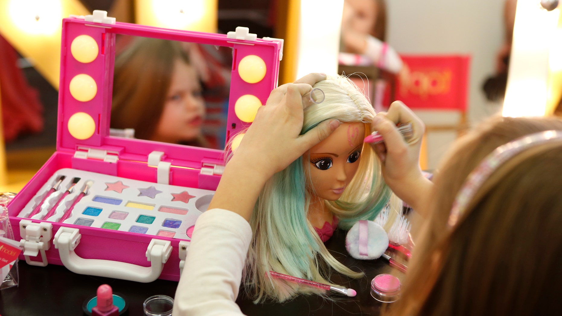 A young girl paints the face of a doll by the company Simba during the press preview of the 66th International Toy Fair in Nuremberg January 27, 2015. (REUTERS/Michaela Rehle)