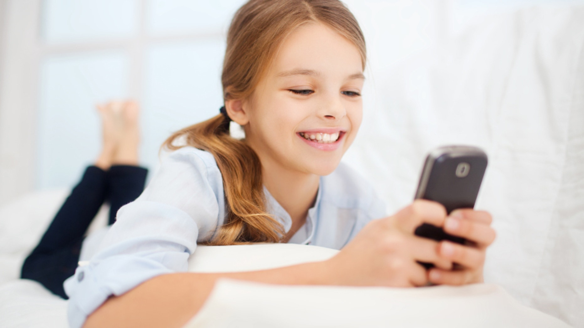 education, school, technology and internet concept - little student girl with smartphone at home