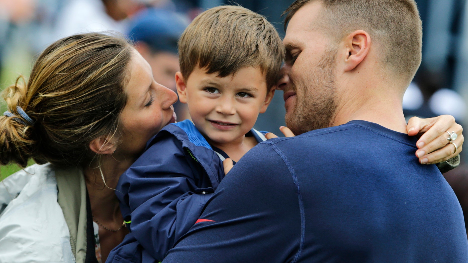 New England Patriots quarterback Tom Brady and his wife Gisele Bundchen embrace their son Benjamin Brady after a joint workout with the Tampa Bay Buccaneers at NFL football training camp, in Foxborough, Mass., Tuesday, Aug. 13, 2013. (AP Photo/Charles Krupa)