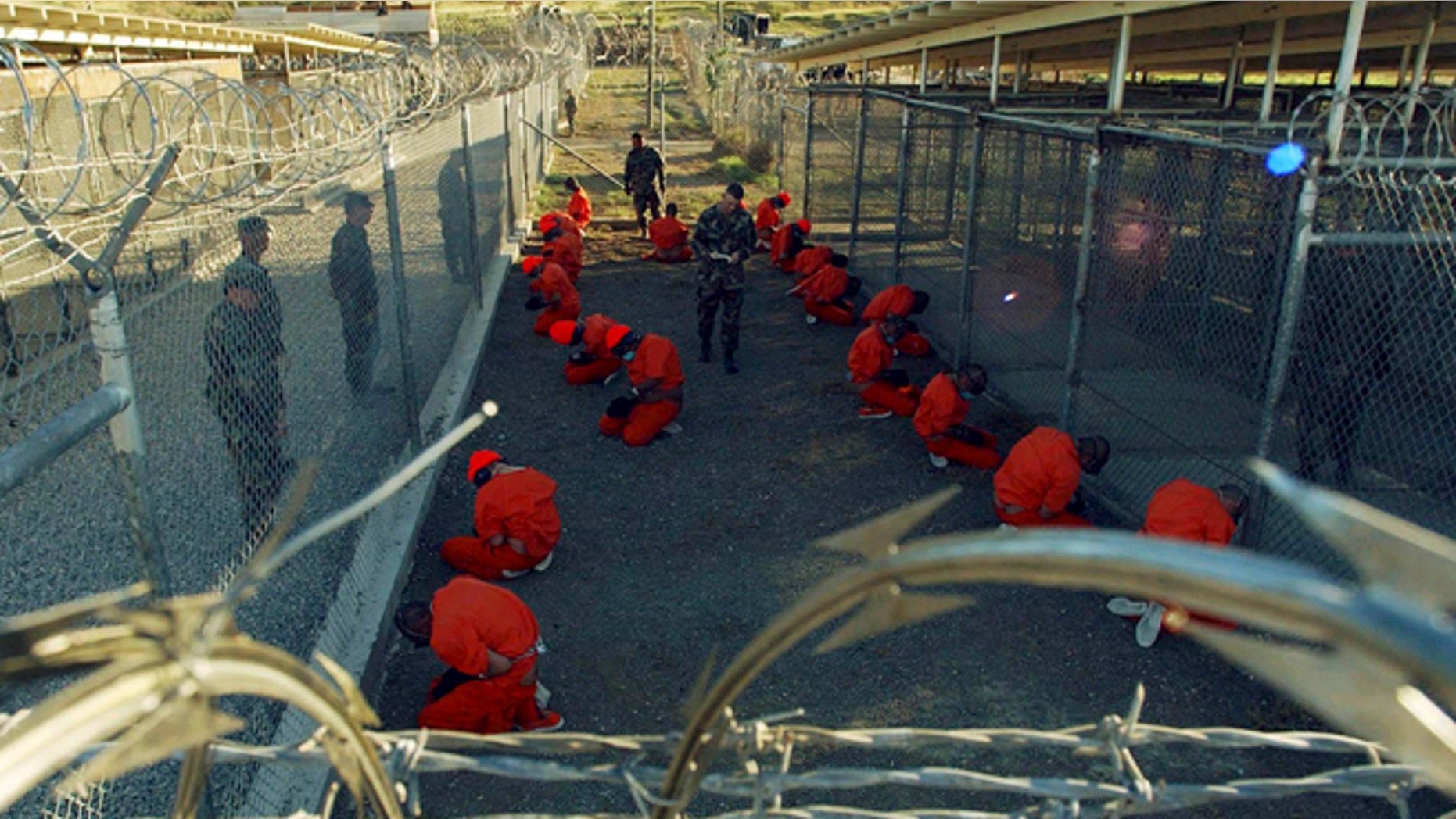 Jan 11, 2002: Detainees in orange jumpsuits sit in a holding area under the watchful eyes of military police during in-processing to the temporary detention facility at Camp X-Ray of Naval Base Guantanamo Bay. (Reuters)
