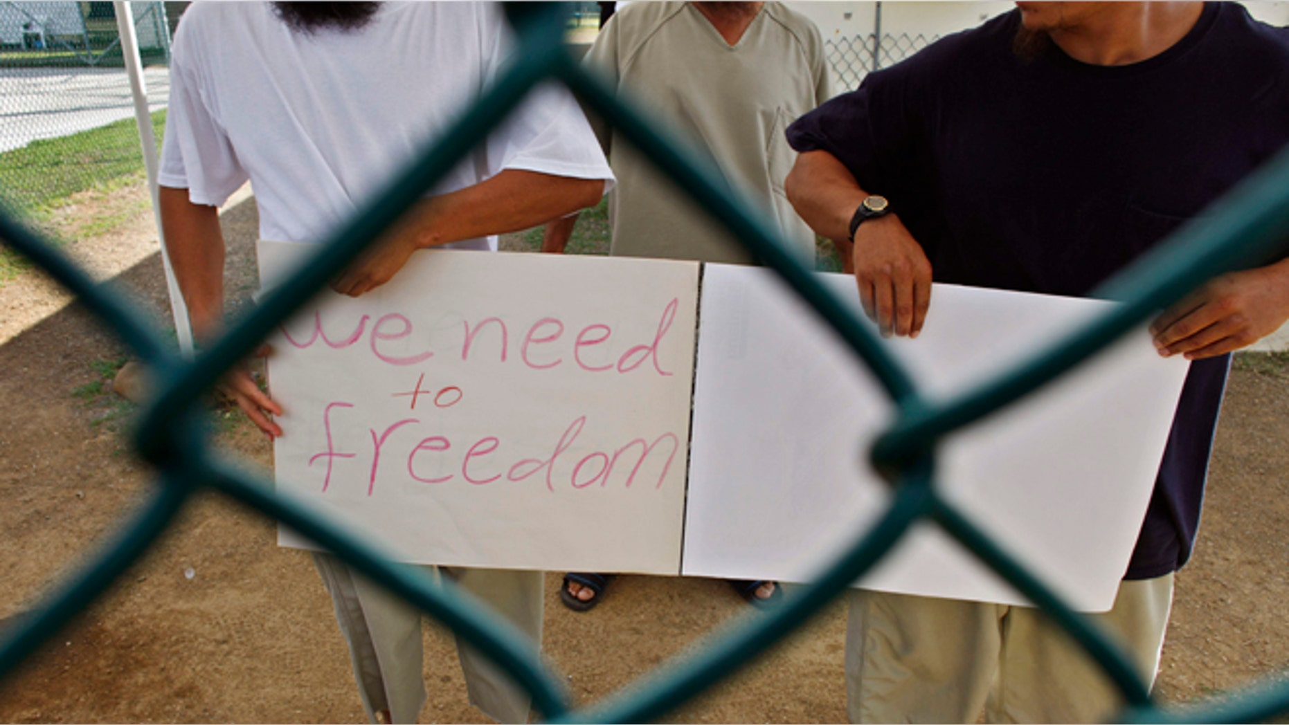 In this June 1, 2009 file photo reviewed by the U.S. military, Chinese Uighur Guantanamo detainees, who at the time were cleared for release but had no country to go to, show a homemade note to visiting members of the media, at Camp Iguana detention facility, at Guantanamo Bay U.S. Naval Base, Cuba. Officials said on Tuesday Dec. 31, 2013, that Slovakia has accepted the last three Chinese Uighur prisoners from Guantanamo Bay who had posed a difficult resettlement challenge. Authorities eventually determined that the 22 Uighurs in its custody had no involvement in terrorism. The men in this photo were resettled at an unknown date. (AP/Brennan Linsley, Pool, File)