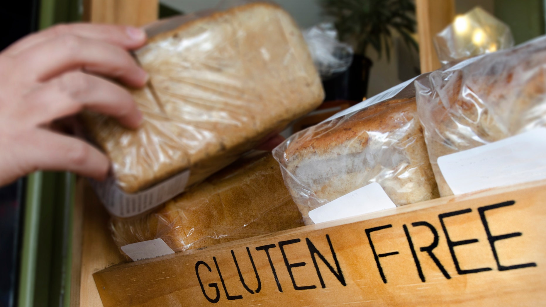 A woman hand picks up a Gluten Free loaf of bread.
