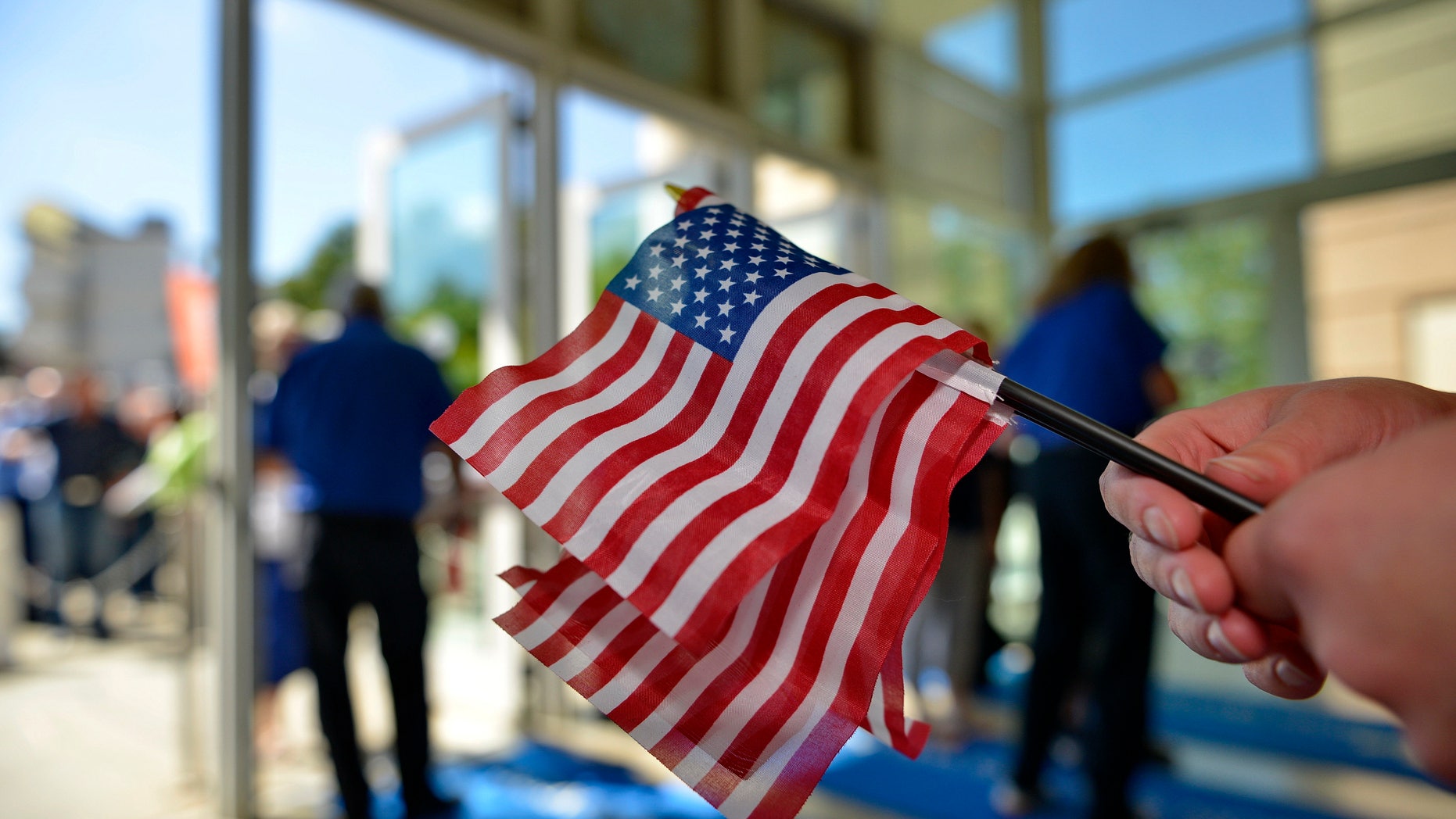 A volunteer passes out American flags to supporters before GOP presidential candidates speak at a forum sponsored by Heritage Action at the Bon Secours Wellness Arena, Friday, Sept. 18, 2015, in Greenville, S.C. (AP Photo/Richard Shiro)