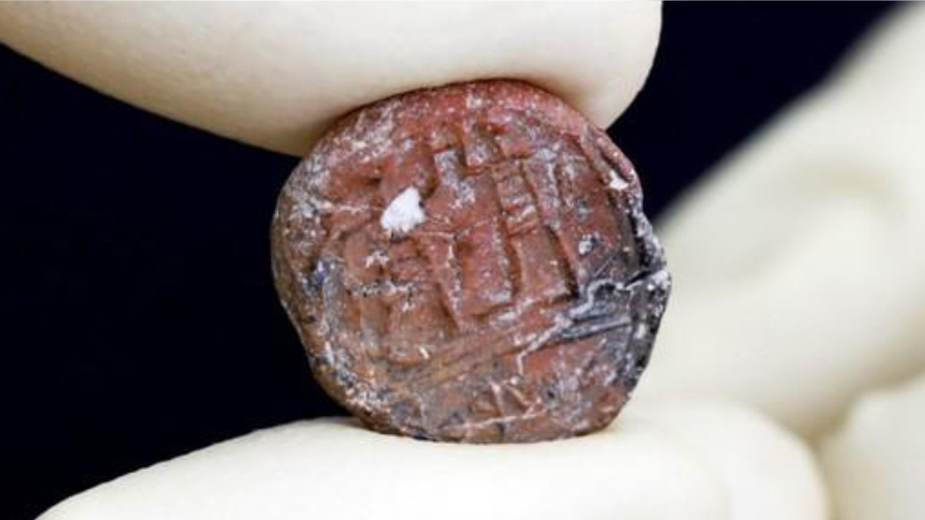 A conservator shows a 2,700-year-old clay seal impression which archaeologists from the Israel Antiquities Authority say belonged to a biblical governor of Jerusalem and was unearthed in excavations in the Western Wall plaza in Jerusalem's Old City January 1, 2018.
