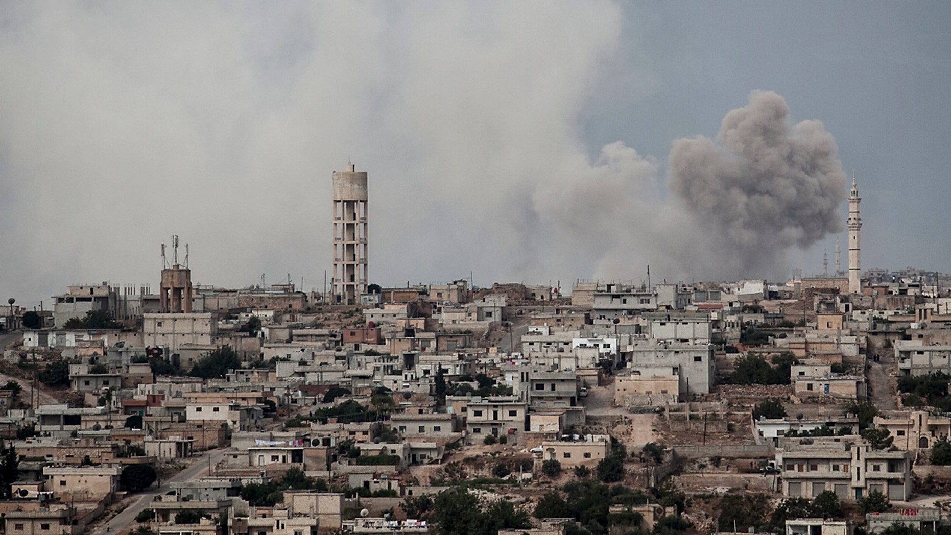FILE 2013: smoke rises after a TNT bomb was thrown from a helicopter, hitting a rebel position during heavy fighting between troops loyal to president Bashar Assad and opposition fighters, in a neighbouring village to Kafr Nabuda, in the Idlib province.