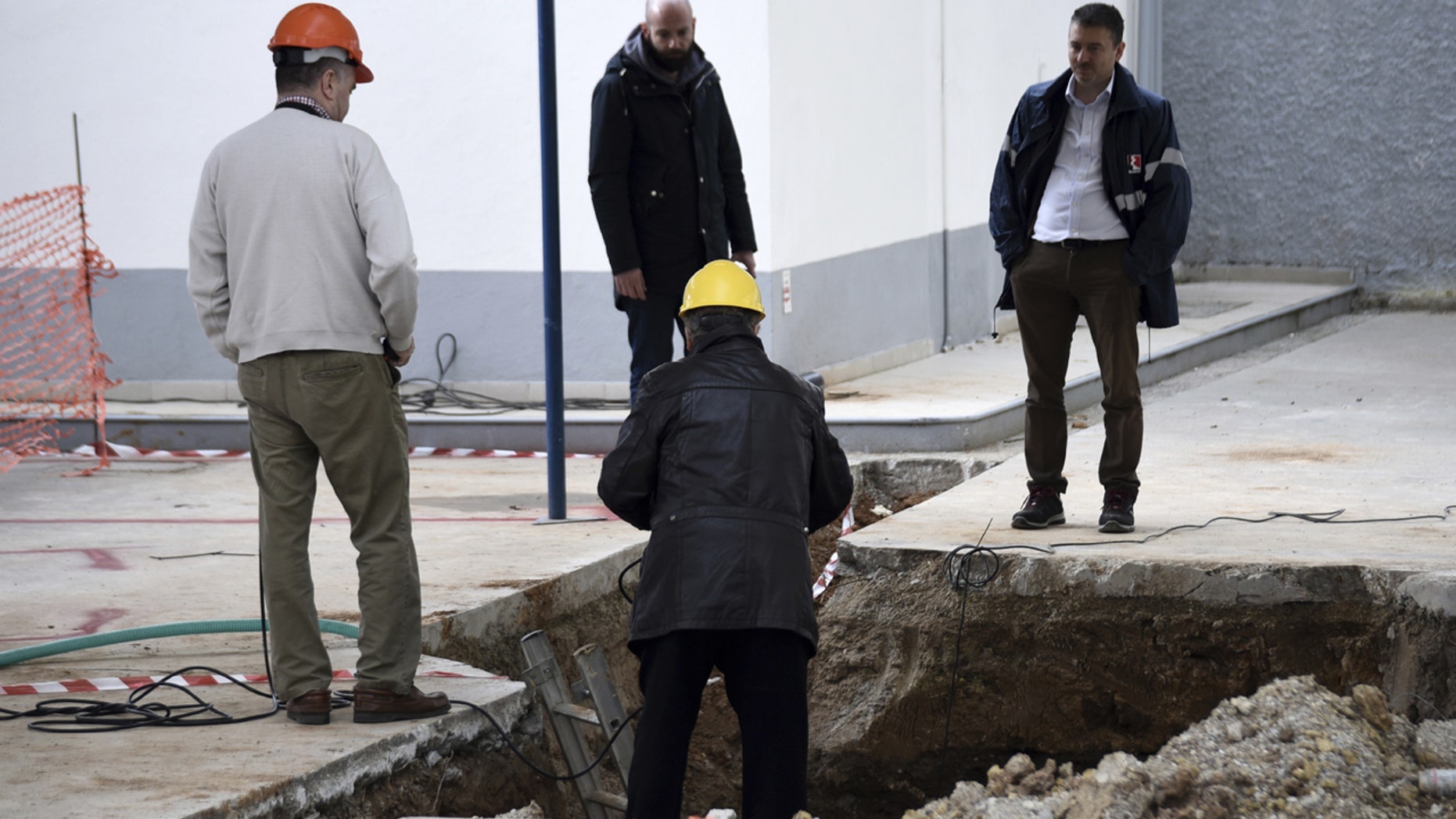 Experts check the location where an unexploded World War II bomb was found 5 meters (over 16 feet) deep, at a gas station in the northern Greek city of Thessaloniki, on Thursday, Feb. 9, 2016.