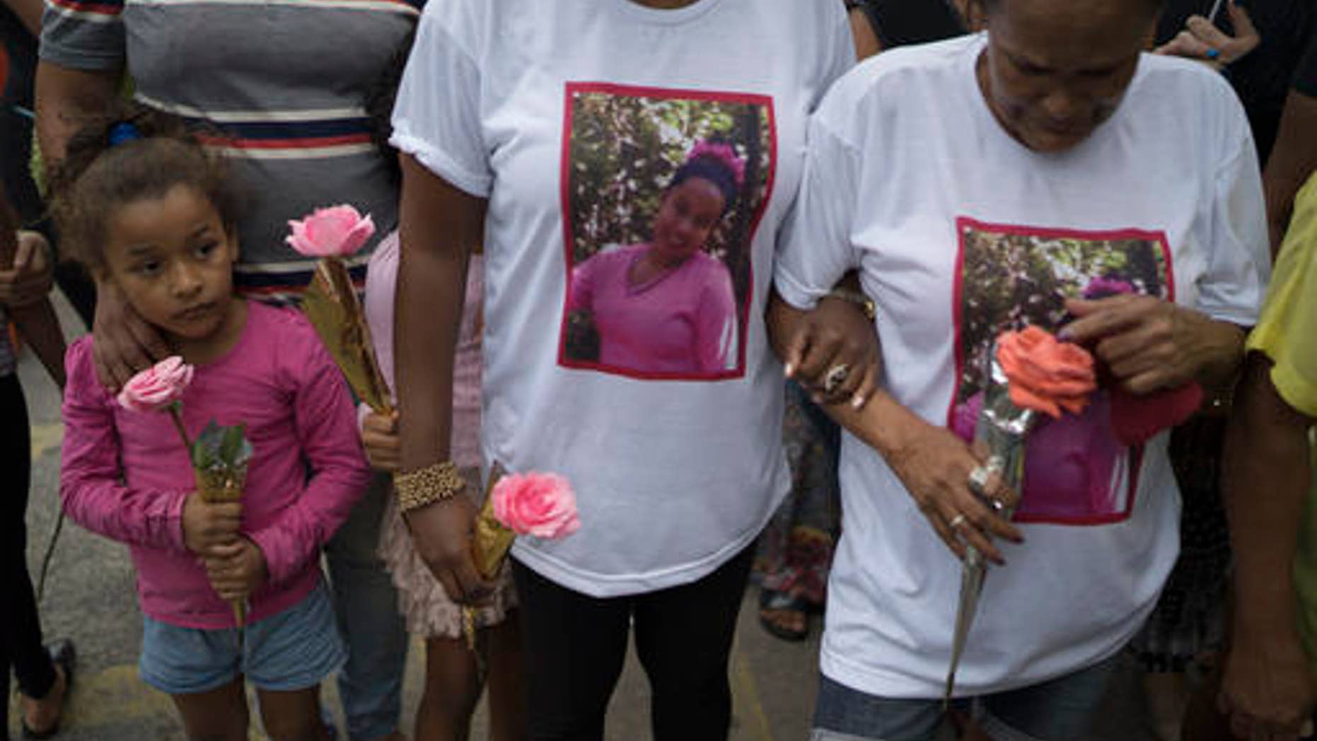Relatives and friends hold roses during the burial service of Bruna Lace de Freitas, who was killed two days earlier by a stray bullet when she was inside her home, in Rio de Janeiro, Brazil, Friday, Oct. 28, 2016. The Brazilian Forum on Public Security says in its 10th annual report that in 2015 more people were murdered in Brazil than have been killed in war-torn Syria. (AP Photo/Leo Correa)