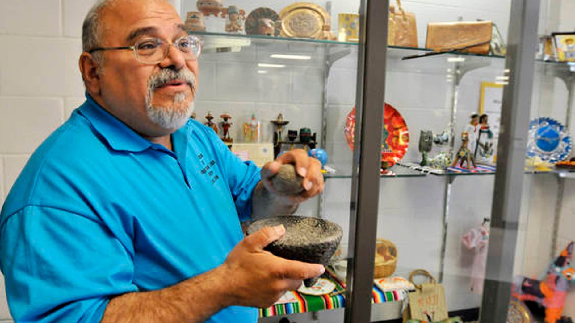Curator Guillermo Arriaga holds a molcajete, a traditional Mexican version of mortar and pestle carved out of volcanic rock, one of the artifacts on display by the Museum of Hispanic and Latino Cultures at Southview Middle School in Lorain, Ohio.