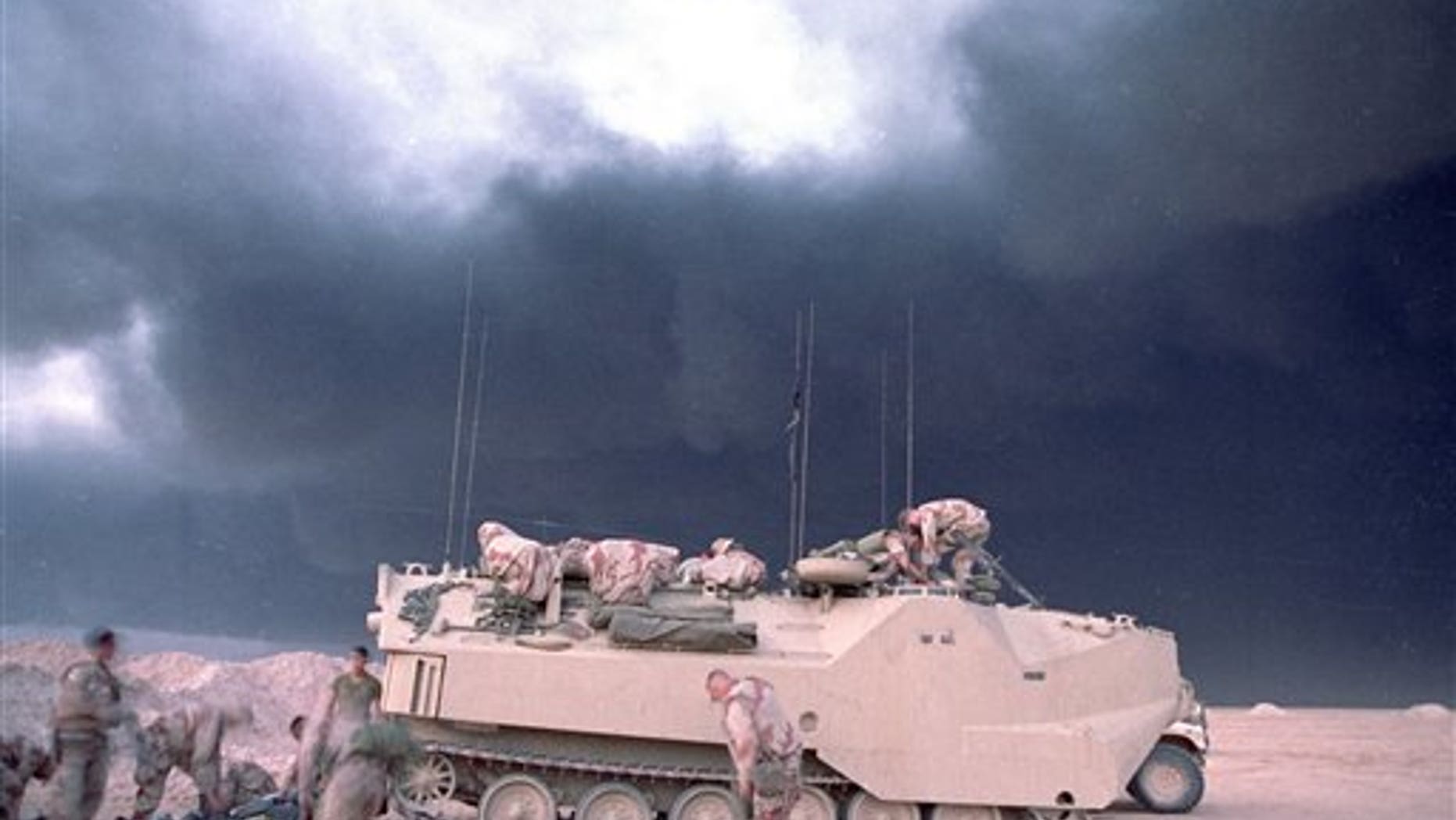 File photo from 1991 shows smoke from a burning oil well in Kuwait billowing upbehind a U.S. Marines armored vehicle.