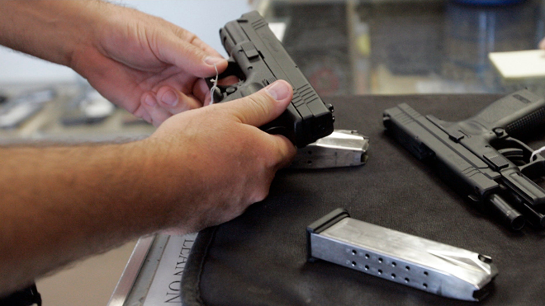 A customer inspects a 9mm handgun at Rink's Gun and Sport in the Chicago, suburb of Lockport, Illinois June 26, 2008. For the first time in U.S. history, the Supreme Court ruled on Thursday that individual Americans have the right to own guns for personal use, and struck down a strict gun control law in the U.S. capital. The landmark 5-4 ruling marked the first time in nearly 70 years the country's high court has addressed whether the Second Amendment of the U.S. Constitution protects an individual right to keep and bear arms, rather than a right tied to service in a state militia. REUTERS/Frank Polich (UNITED STATES) - RTX7DDO