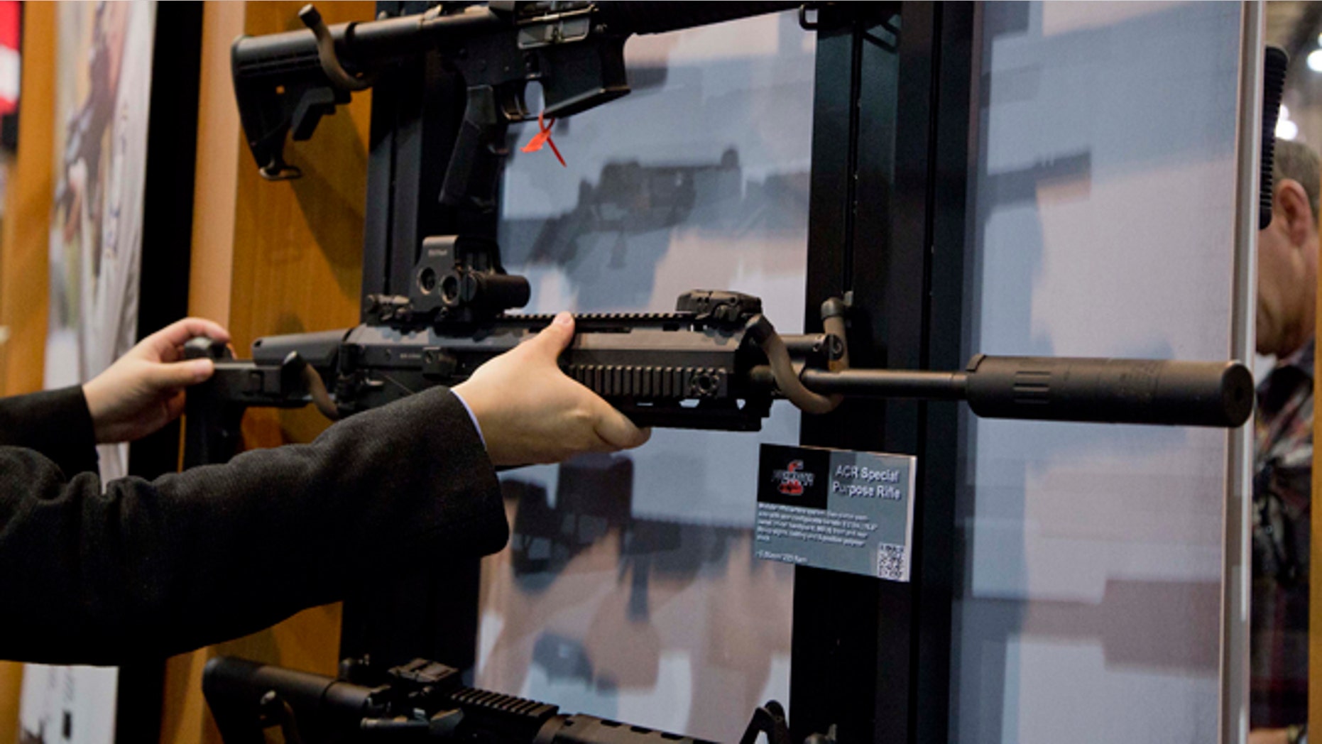 Jan. 15, 2013: Accessories manufacturer Kevin Kao, of Irvine, Calif., examines a military grade Remington ACR Special Purpose Rifle at the 35th annual SHOT Show in Las Vegas.