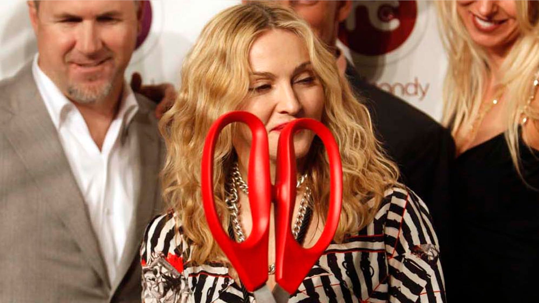 U.S. singer Madonna, front, holds up scissors to cut the ribbon as she poses for pictures during the opening of Hard Candy Fitness, her new gym in Mexico City, Monday Nov. 29, 2010. (AP Photo/Miguel Tovar)