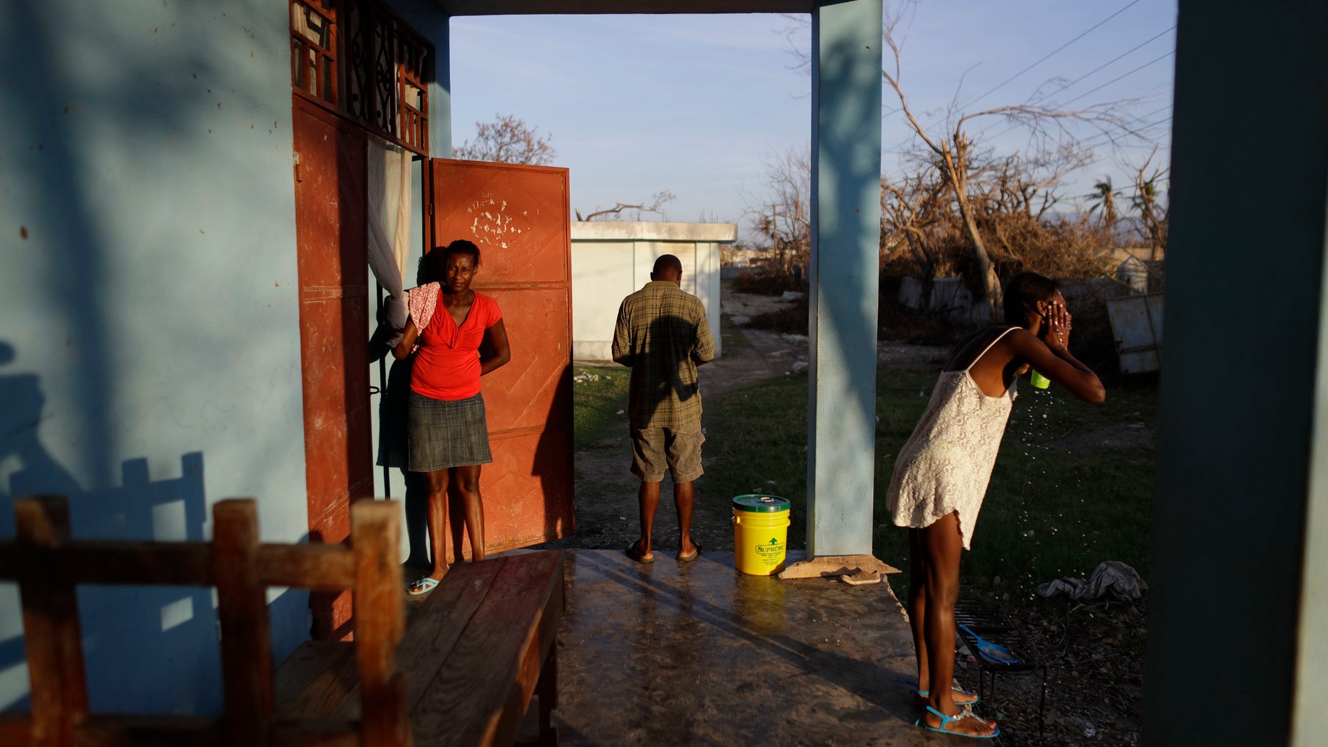 People whose homes were destroyed by Hurricane Matthew begin their day at a school where they have sought shelter in Port Salut, Haiti, Tuesday, Oct. 11, 2016. While some families like these were able to recover mattresses, furniture, and household goods from under the mud, others lost everything. The scores of people sheltering at this school have been told they have one more week before they have to move out so classes can restart. (AP Photo/Rebecca Blackwell)