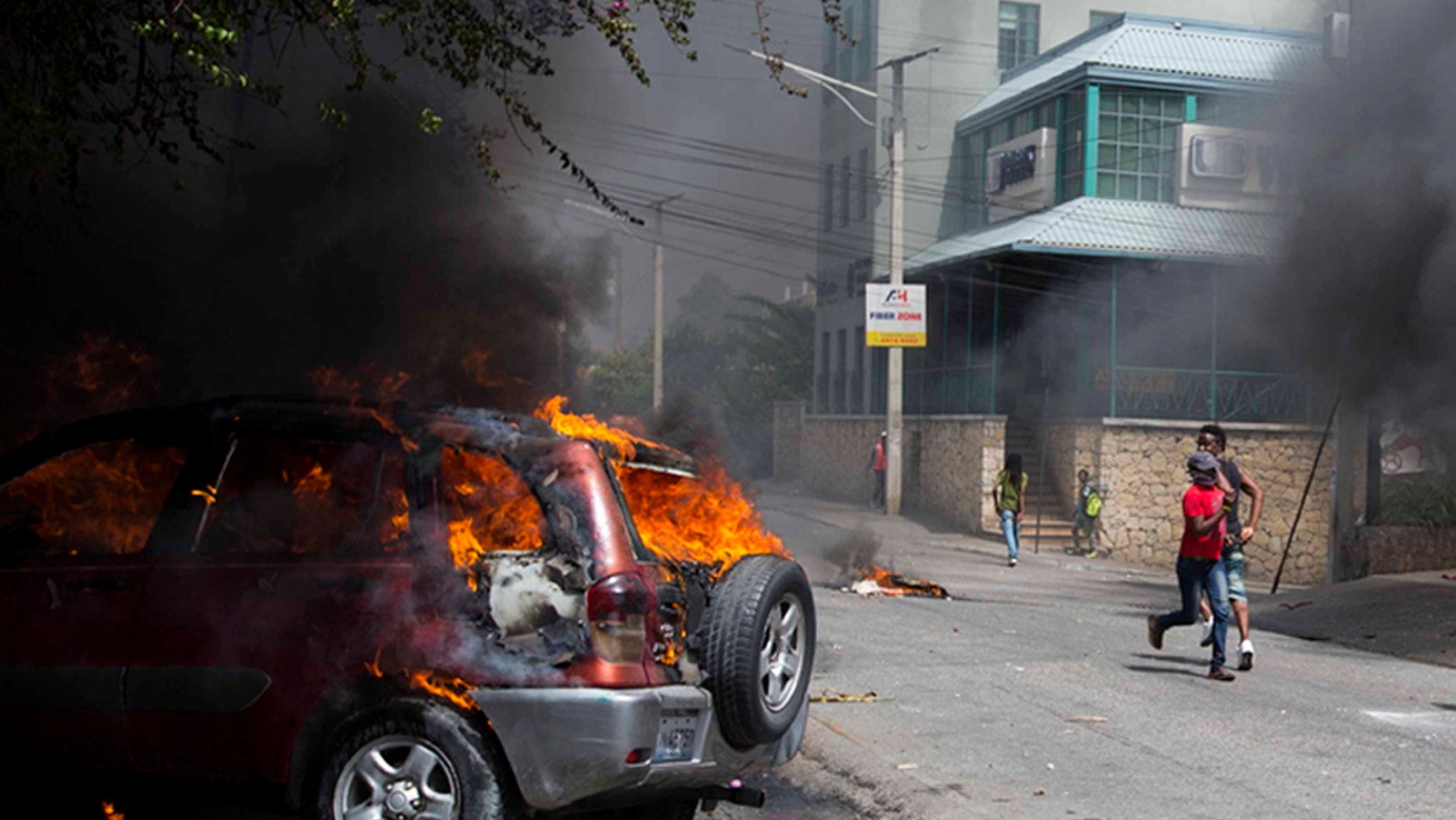 People run past the Best Western hotel during a protest over the cost of fuel in Port-au-Prince, Haiti, Saturday, July 7, 2018.