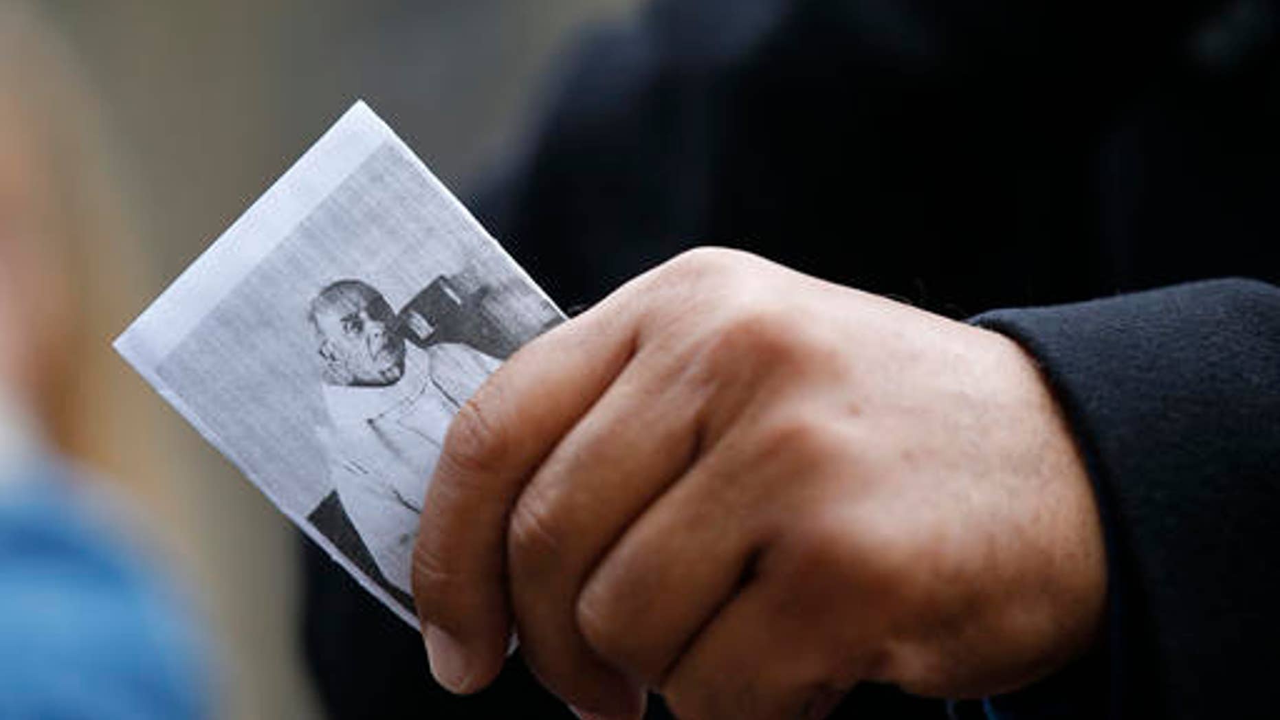 A man holds a religious leaflet showing the priest Jacques Hamel during his funeral mass, outside the Rouen cathedral, Normandy, Tuesday, Aug.2, 2016. Father Jacques Hamel, 85, was killed by two ISIS extremists as he celebrated morning Mass.