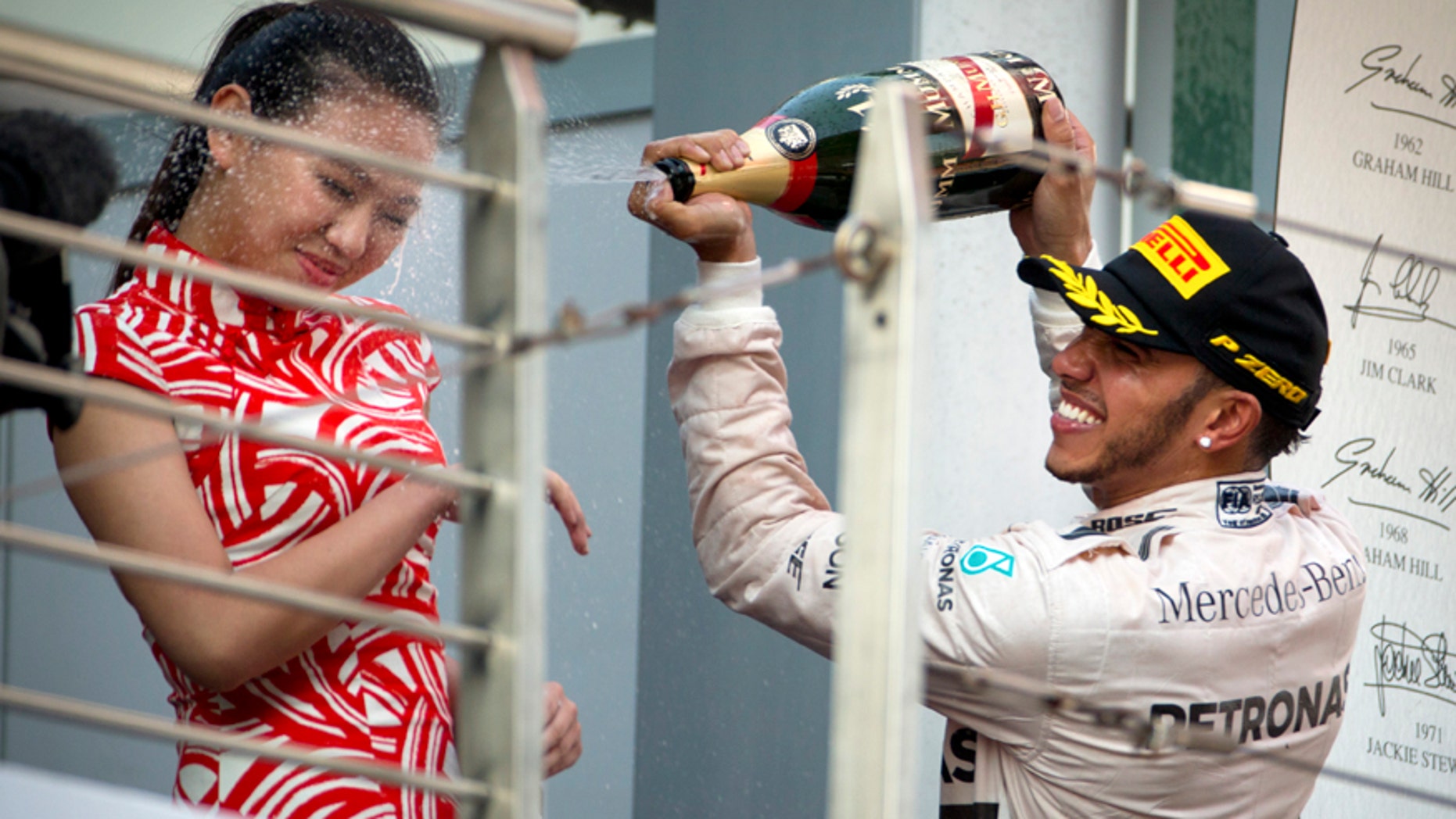 Mercedes driver Lewis Hamilton of Britain sprays champagne on a track attendant on the podium after winning the Chinese Formula One Grand Prix at Shanghai International Circuit in Shanghai, China, Sunday, April 12, 2015. (AP Photo/Mark Schiefelbein)
