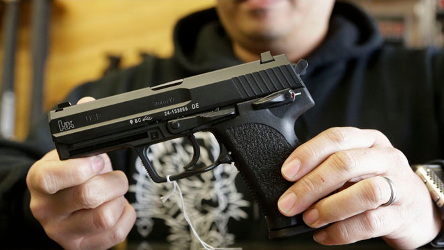 Dec. 19, 2012: A gun store worker holds up an HK USP 9mm handgun at High Bridge Arms Inc. in San Francisco.