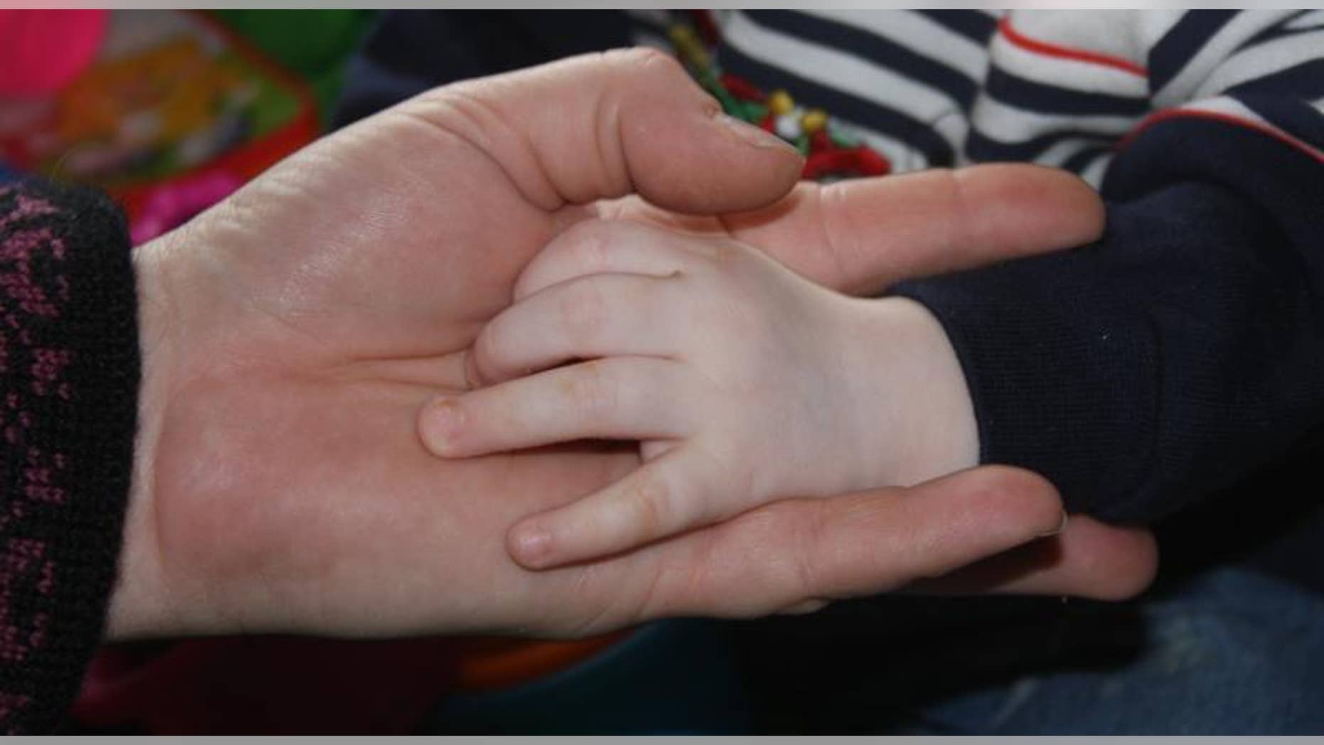 Ann Bates, of Bernville, Pa., holds the hands of the 18-month-old Russian boy she hopes to adopt.