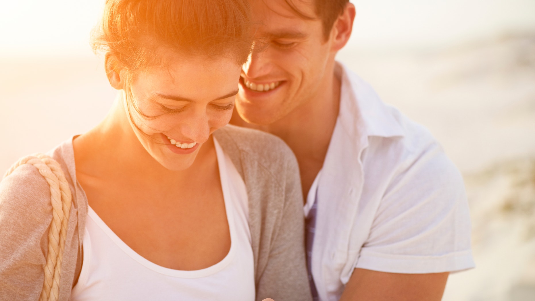 beautiful young couple sharing intimate moment smiling on beach