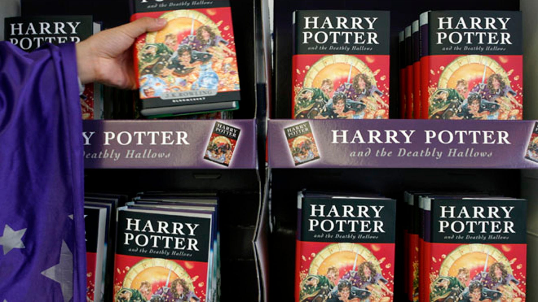 An employee dressed up as a character from the Harry Potter series grabs a copy of the seventh and final Harry Potter book.