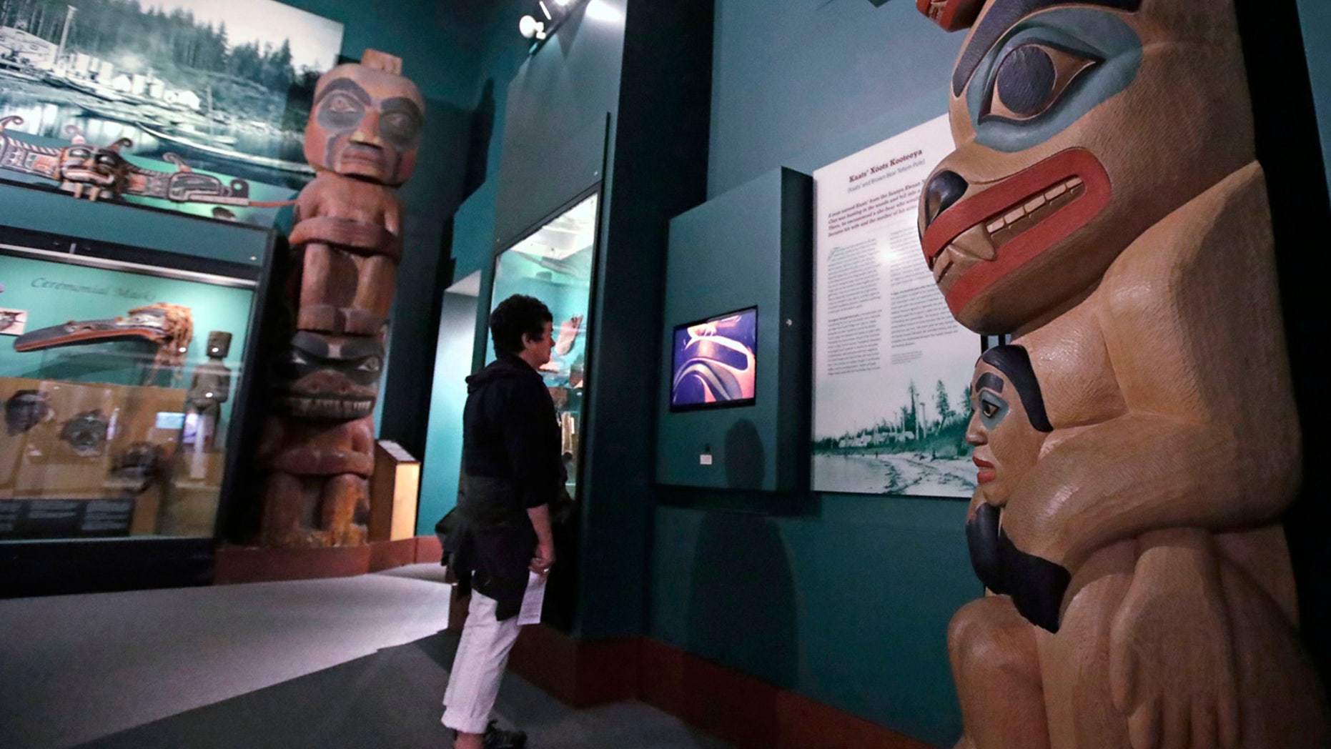 A visitor stands among totem poles as she watches a video as part of Hall of the North American Indian exhibit, at the Peabody Museum of Archaeology & Ethnology at Harvard University in Cambridge, Mass., Thursday, Oct. 13, 2016.