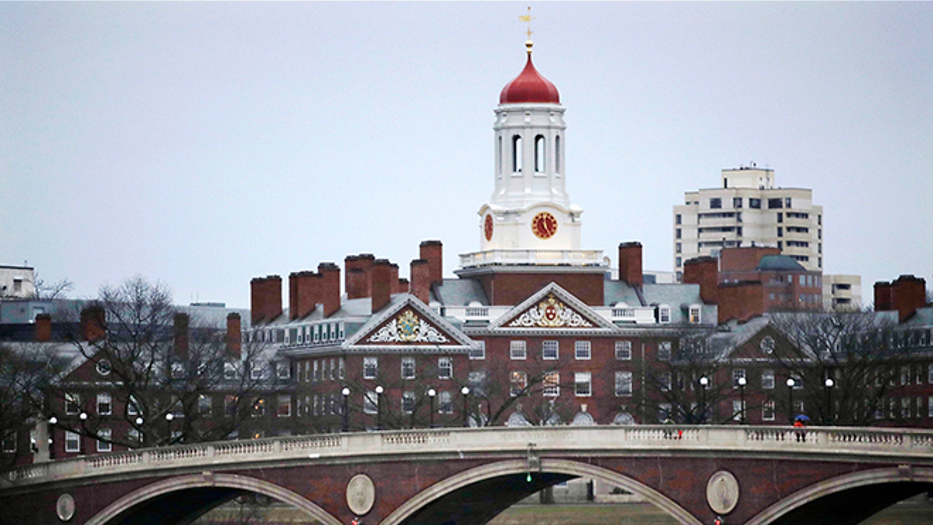FILE - In this March 7, 2017 file photo, rowers paddle along the Charles River past the Harvard College campus in Cambridge, Mass. In a Wednesday, July 12, 2017 recommendation, a Harvard University faculty committee proposed in a a ban on all student fraternities, sororities and single-gender clubs. The proposal would take effect for incoming freshmen in 2018. (AP Photo/Charles Krupa, File)